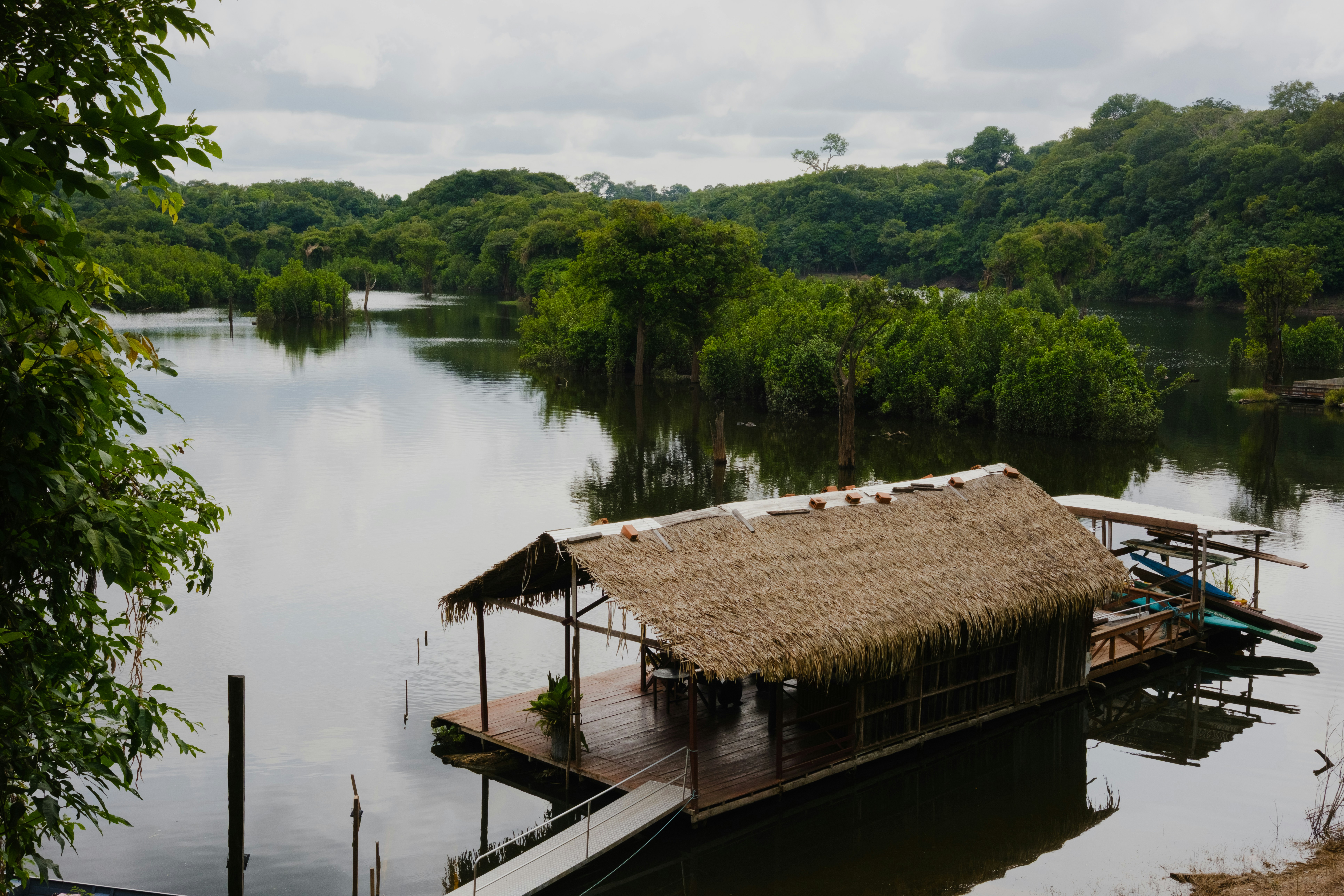 Thatched roof hut on a calm lake surrounded by trees.