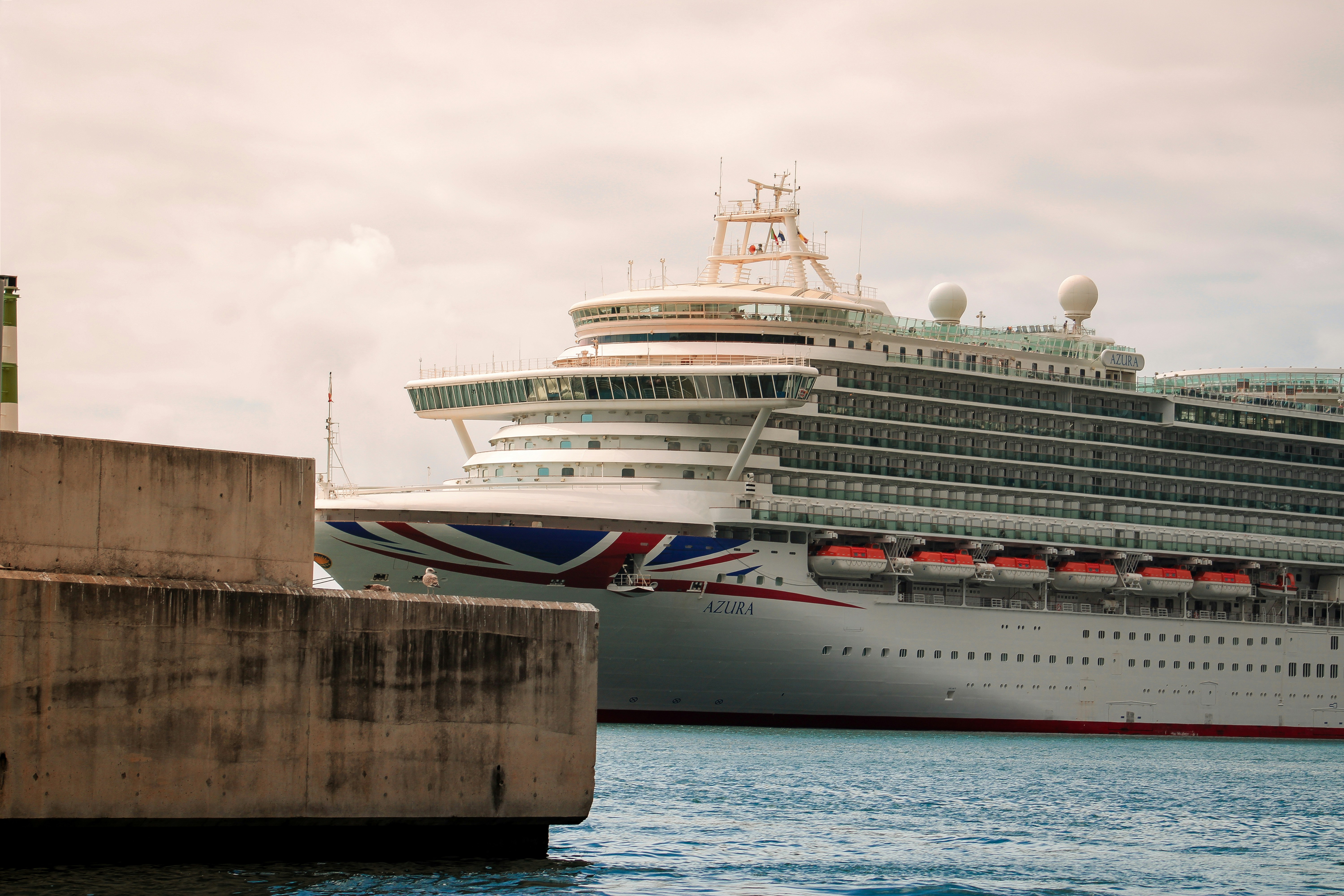 A large white cruise ship docked at a harbor.