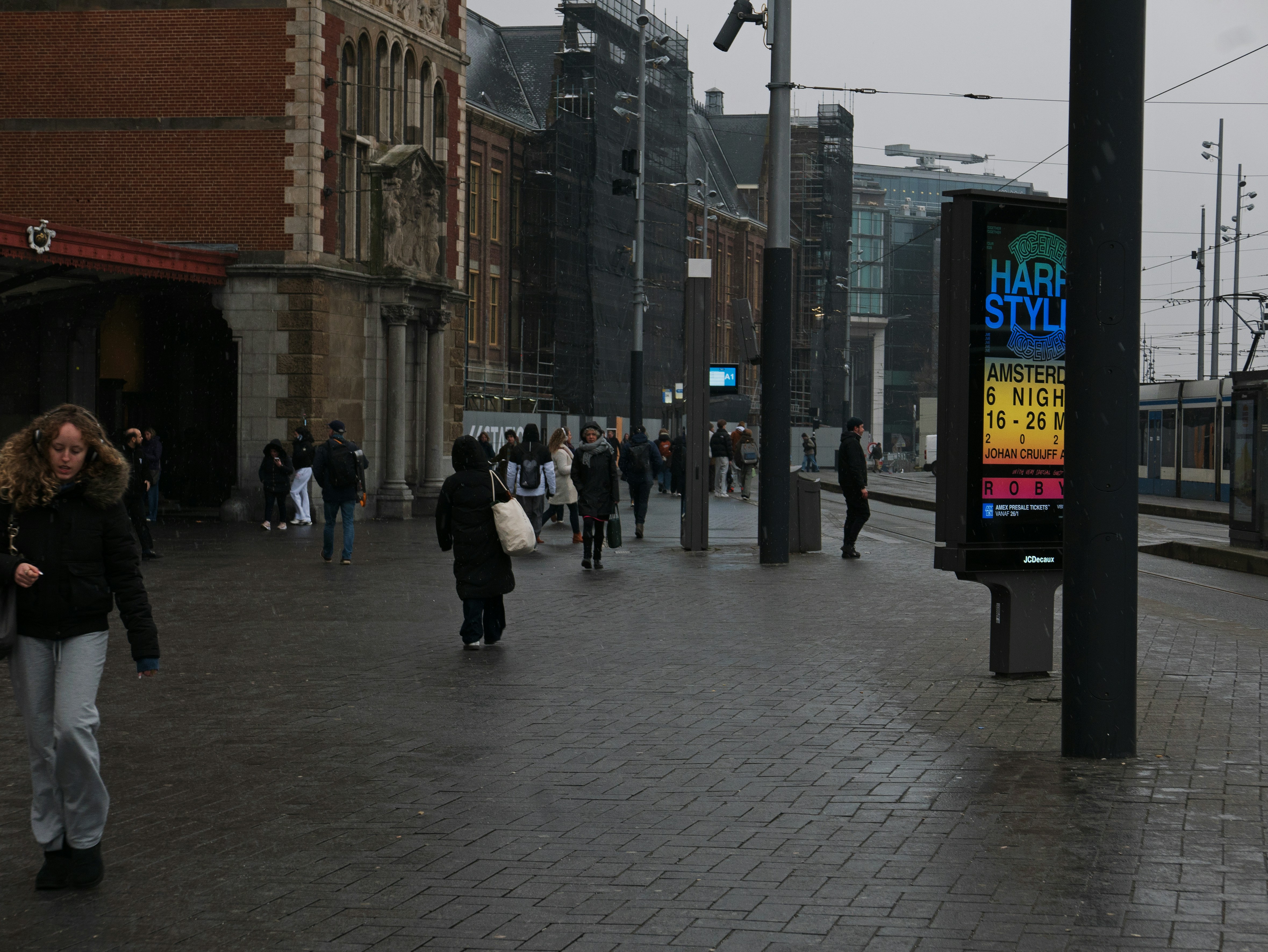 People walking on a wet city street near a building.