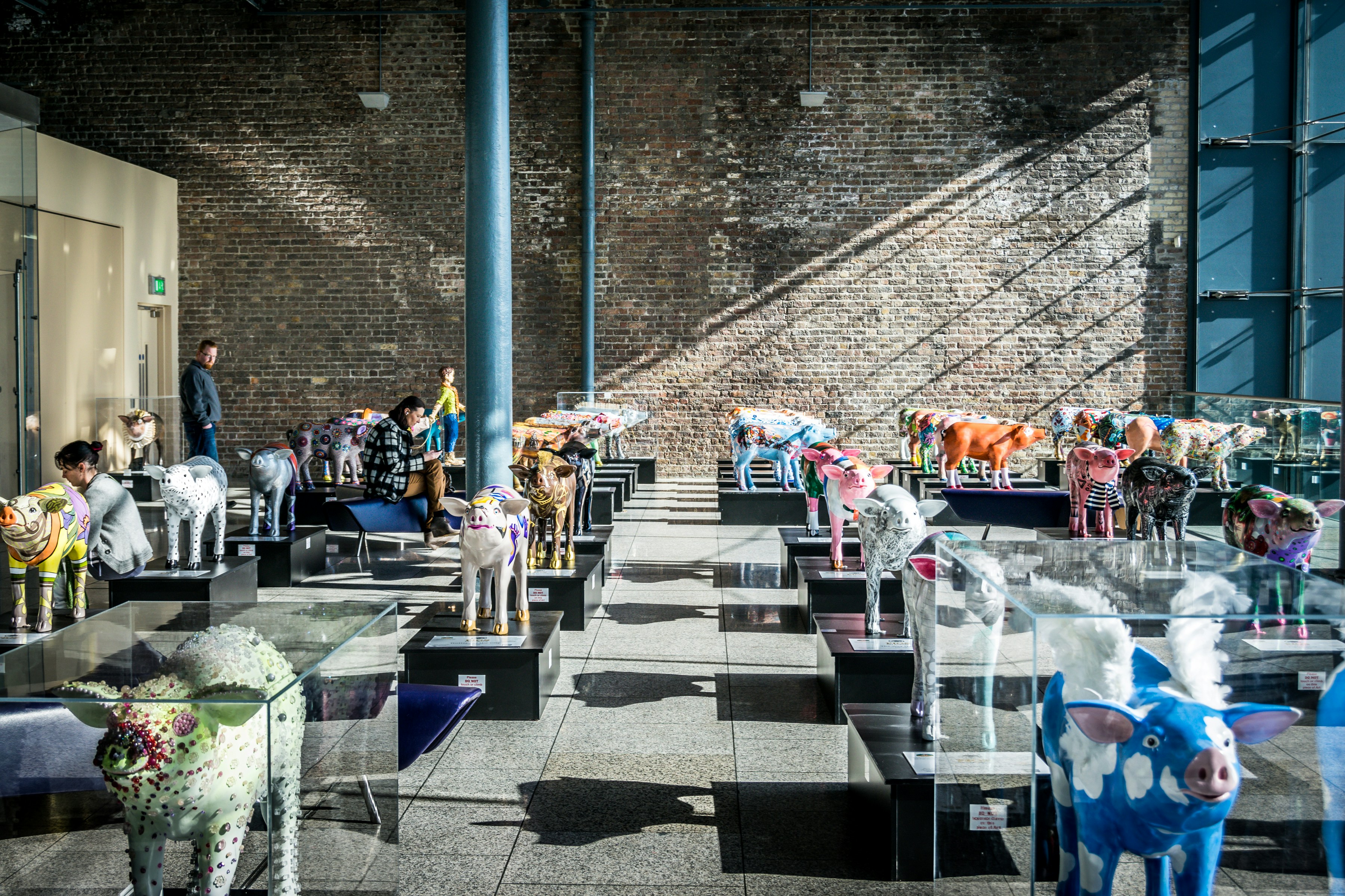 Colorful decorated cow sculptures displayed indoors.