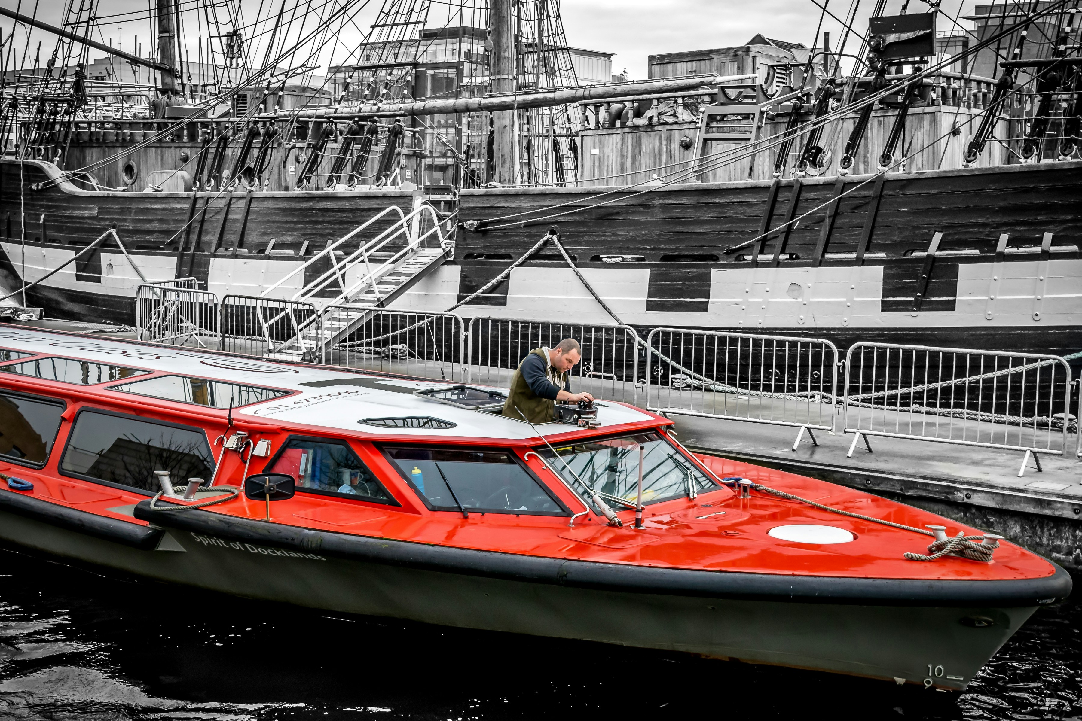 Red boat docked next to a large ship