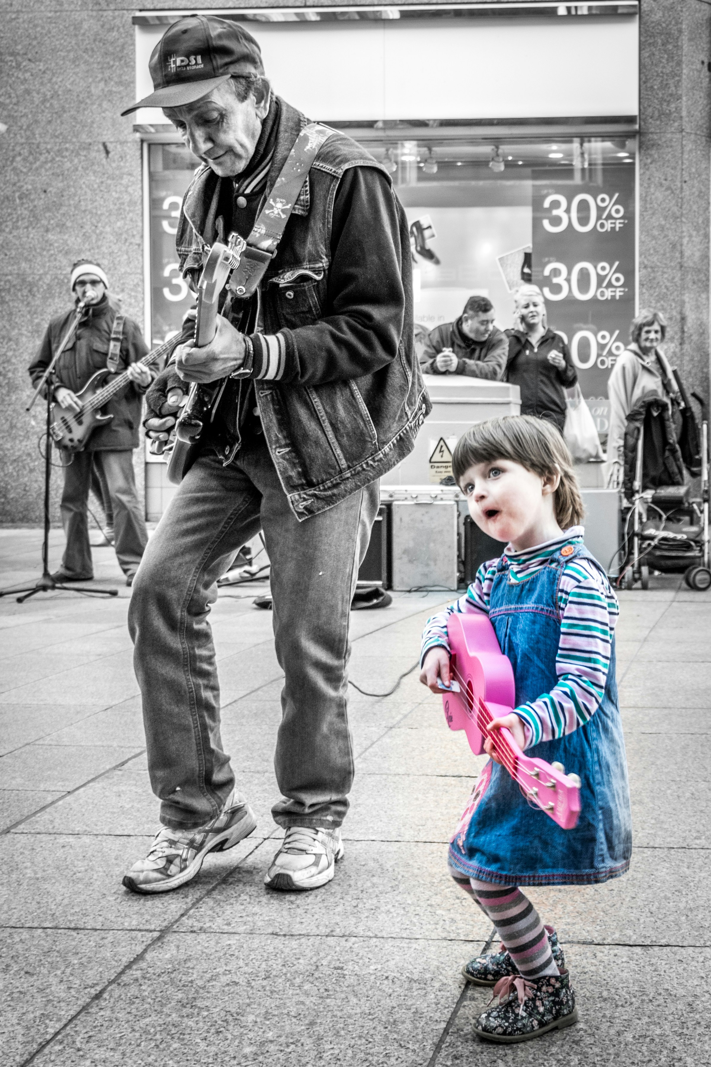 Musicians performing on street with a child dancing