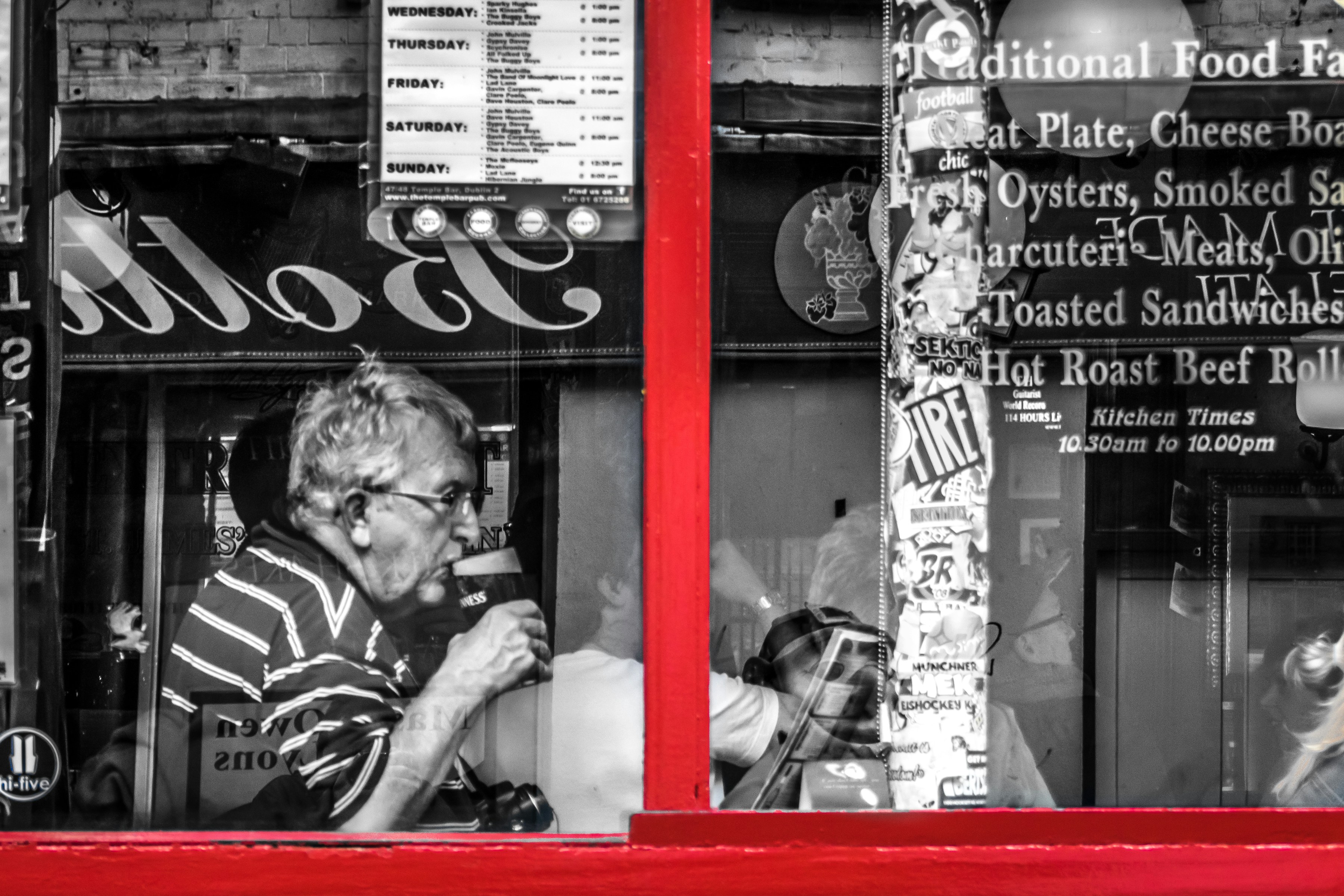 Man drinks at a window with red frame