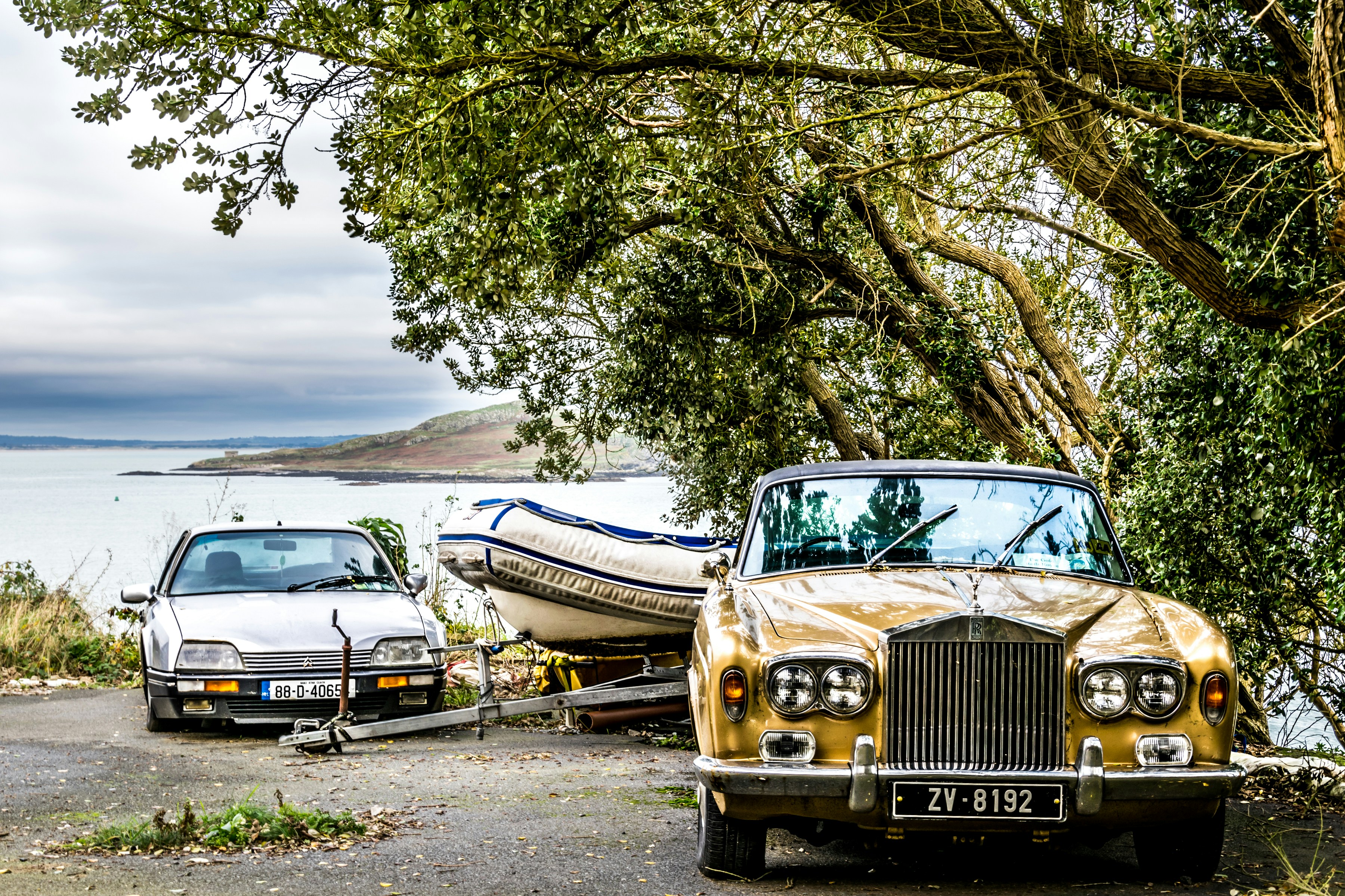 Two vintage cars and a boat by the water