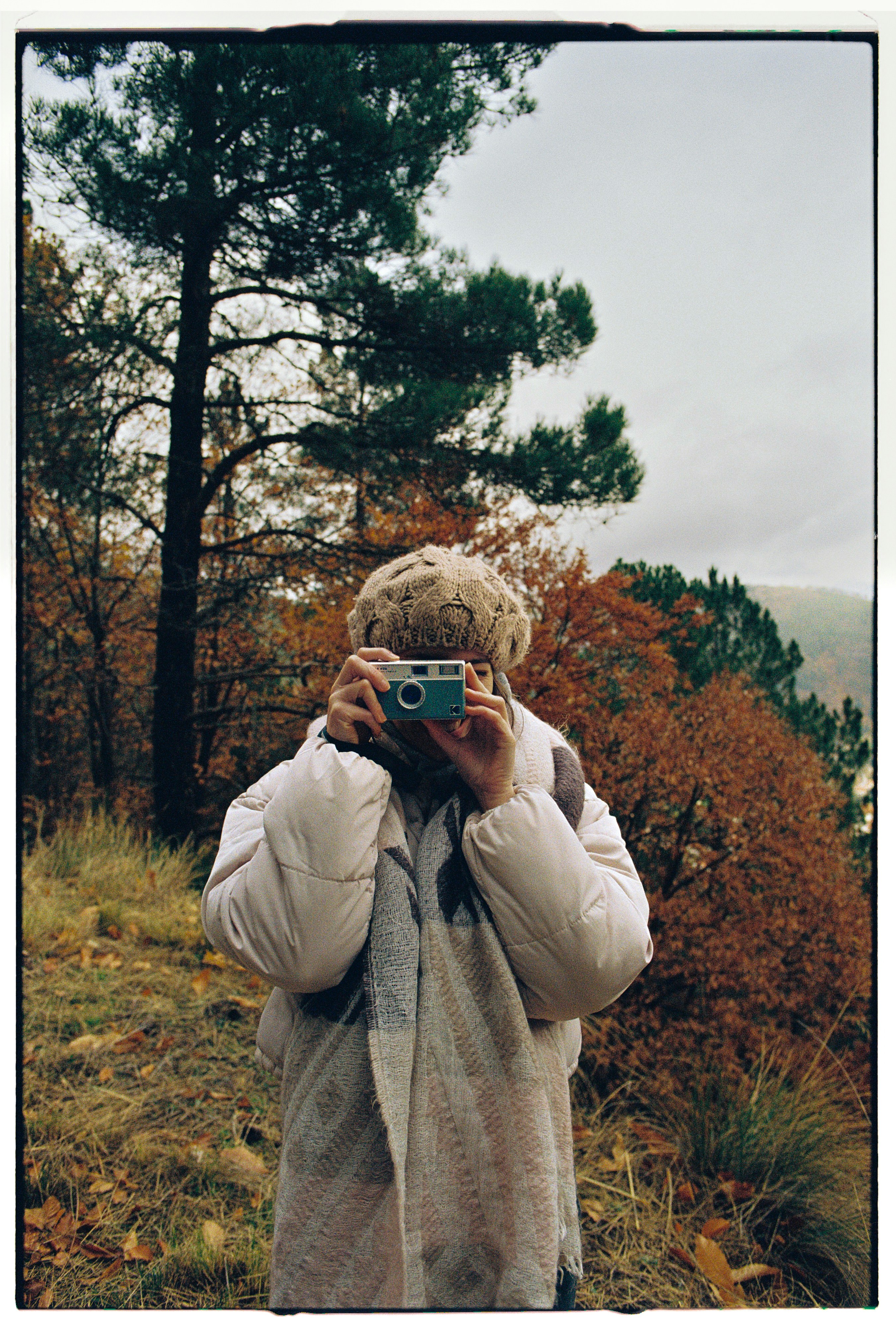 Person taking a selfie with a camera in autumn.