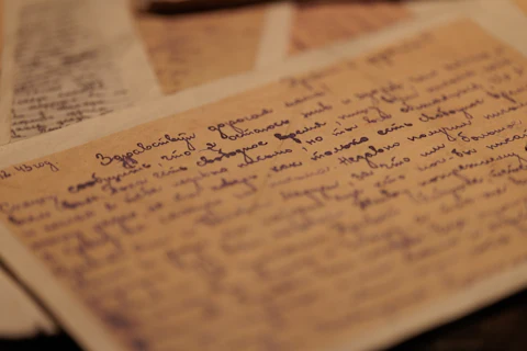 Aged yellow paper covered in cursive handwriting in dark blue ink, photographed as a museum exhibit detail