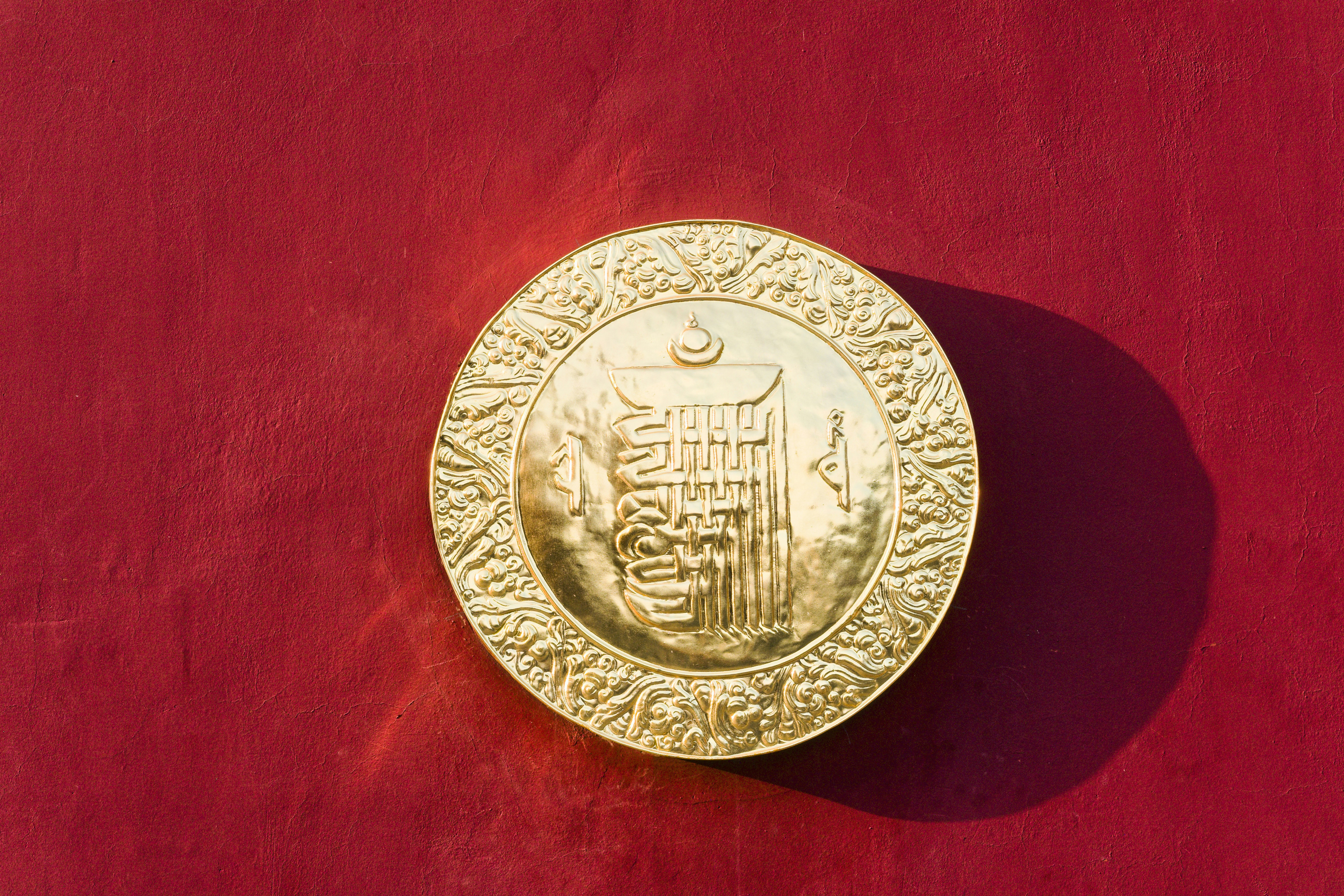 赤い背景に精巧な模様が施された金のメダリオン