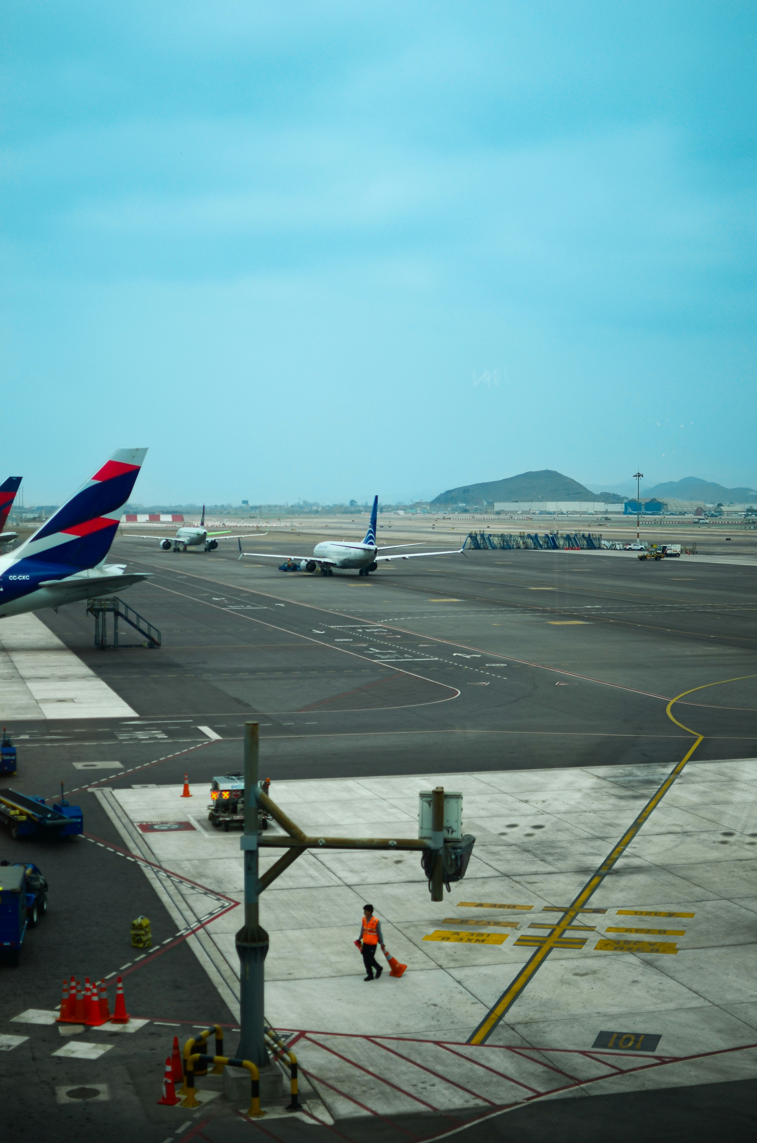 Airport tarmac with planes and a worker sweeping