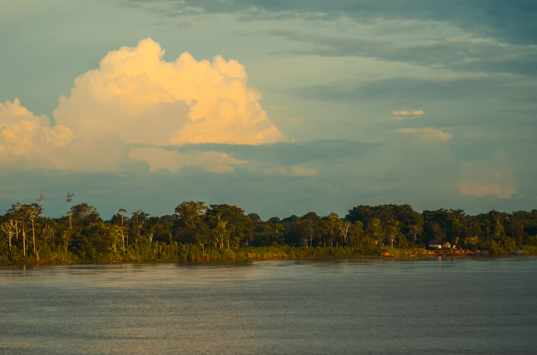 Wide Amazon river at golden hour, towering clouds over the jungle