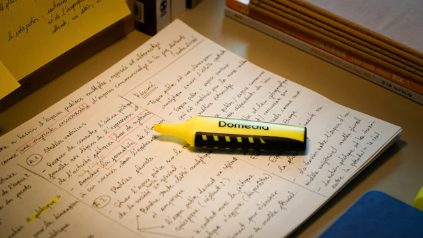 A yellow highlighter rests on handwritten notes.