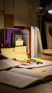 Desk with open book, laptop, and study materials.