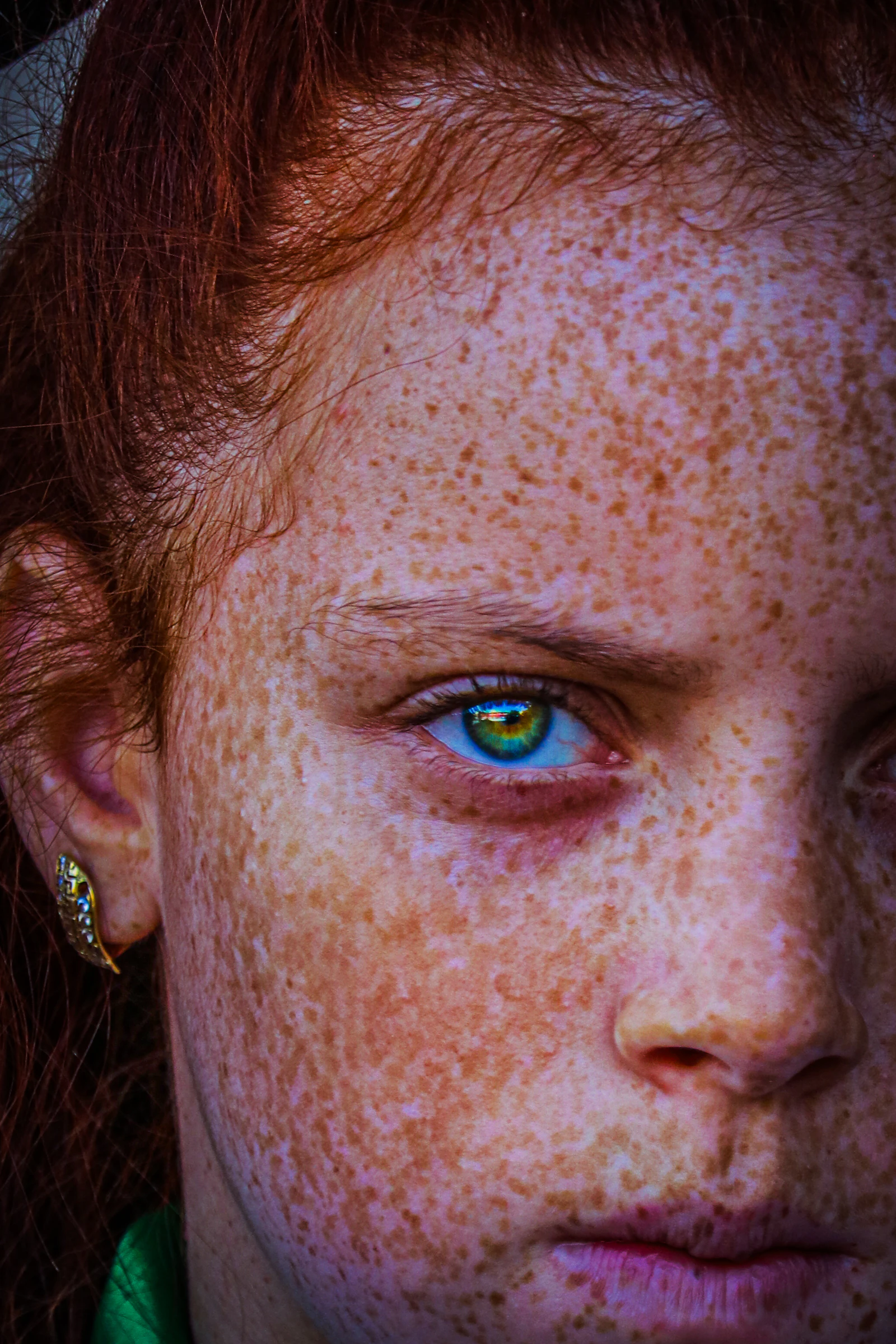 Close-up portrait with soft freckling across the cheek in warm natural light — a calm study of pigmentation