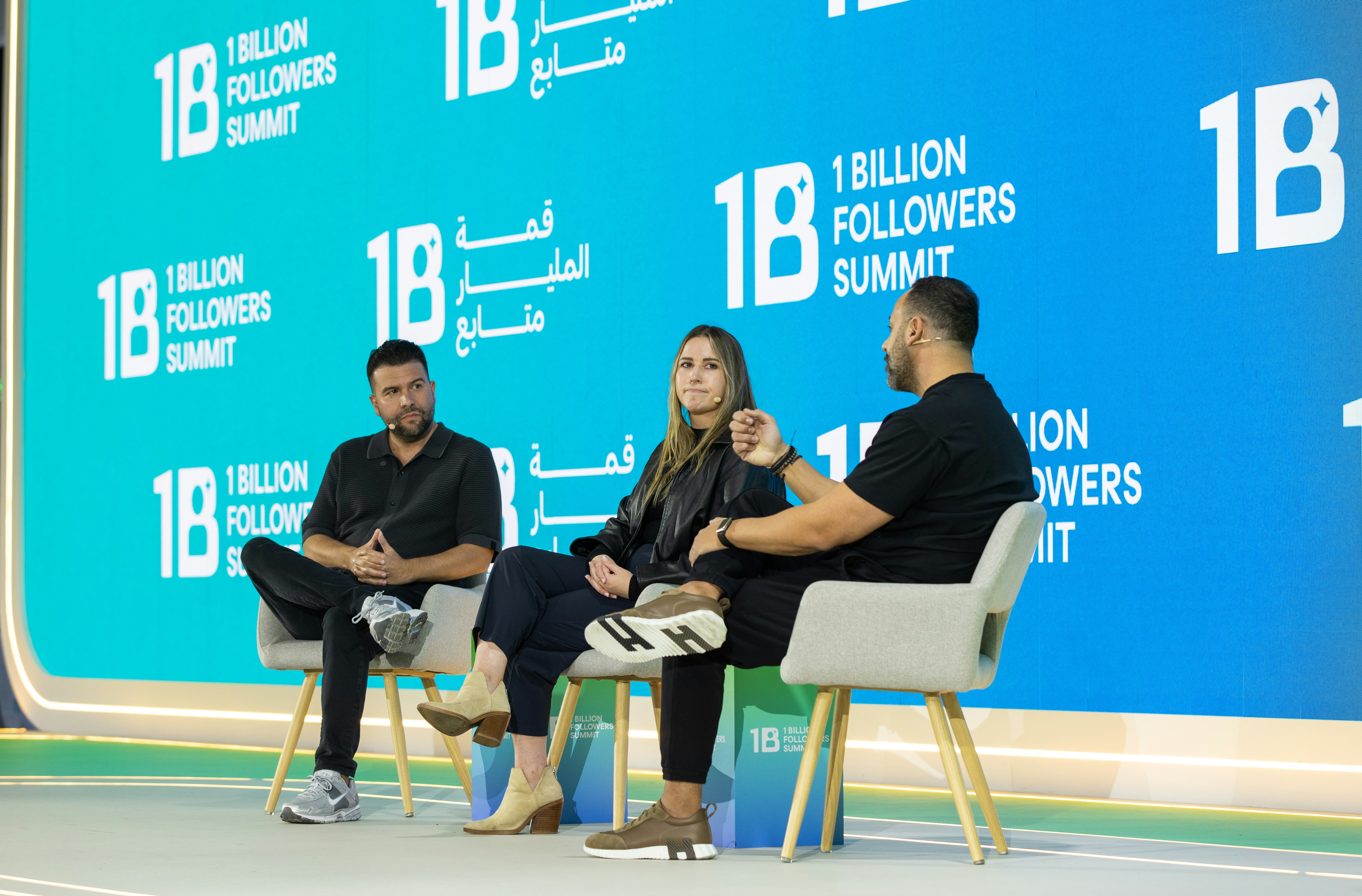 Three people sit on chairs on a stage discussing.