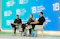 Three people sit on chairs on a stage discussing.