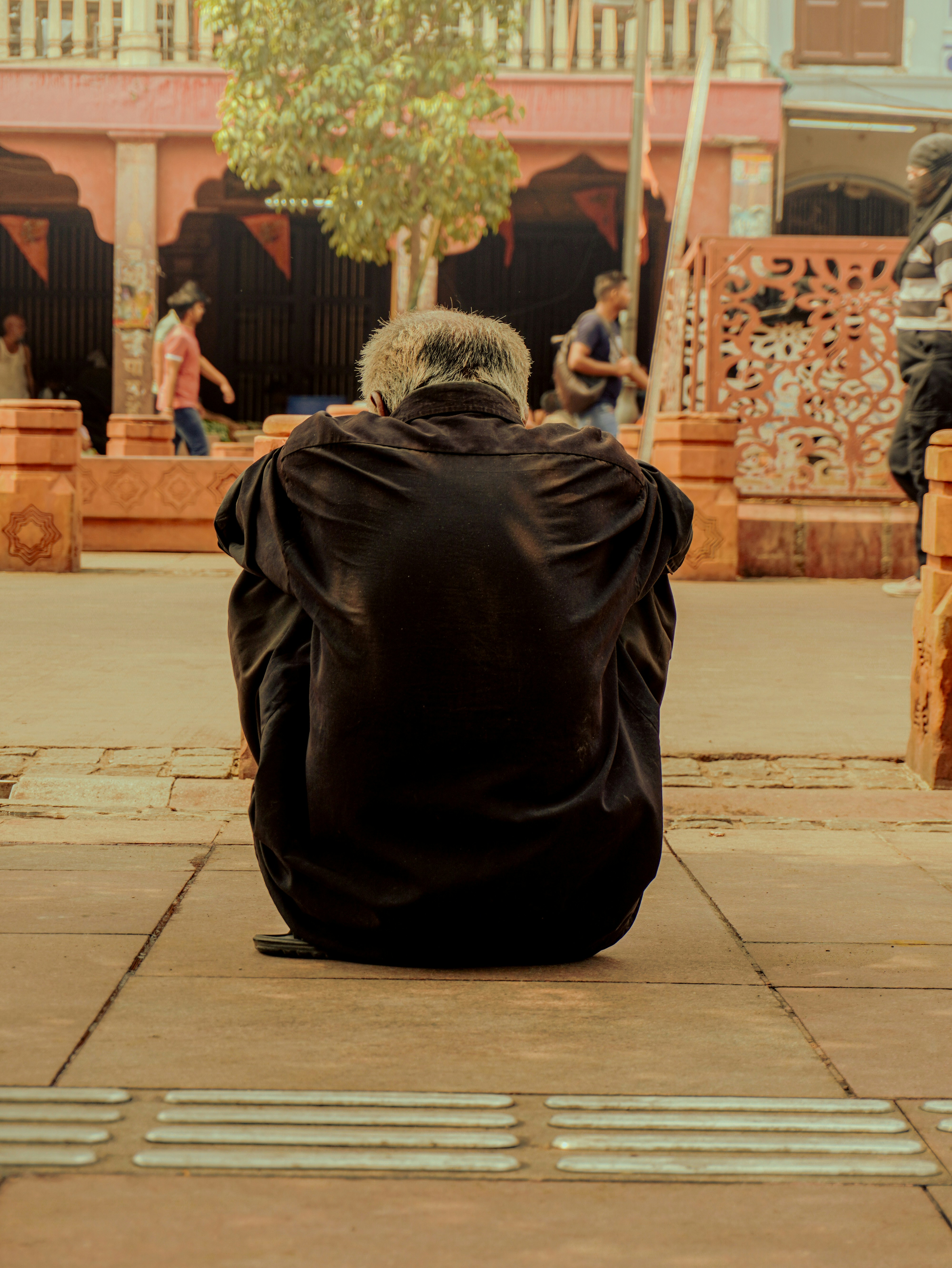 Man in black shirt sits on sidewalk