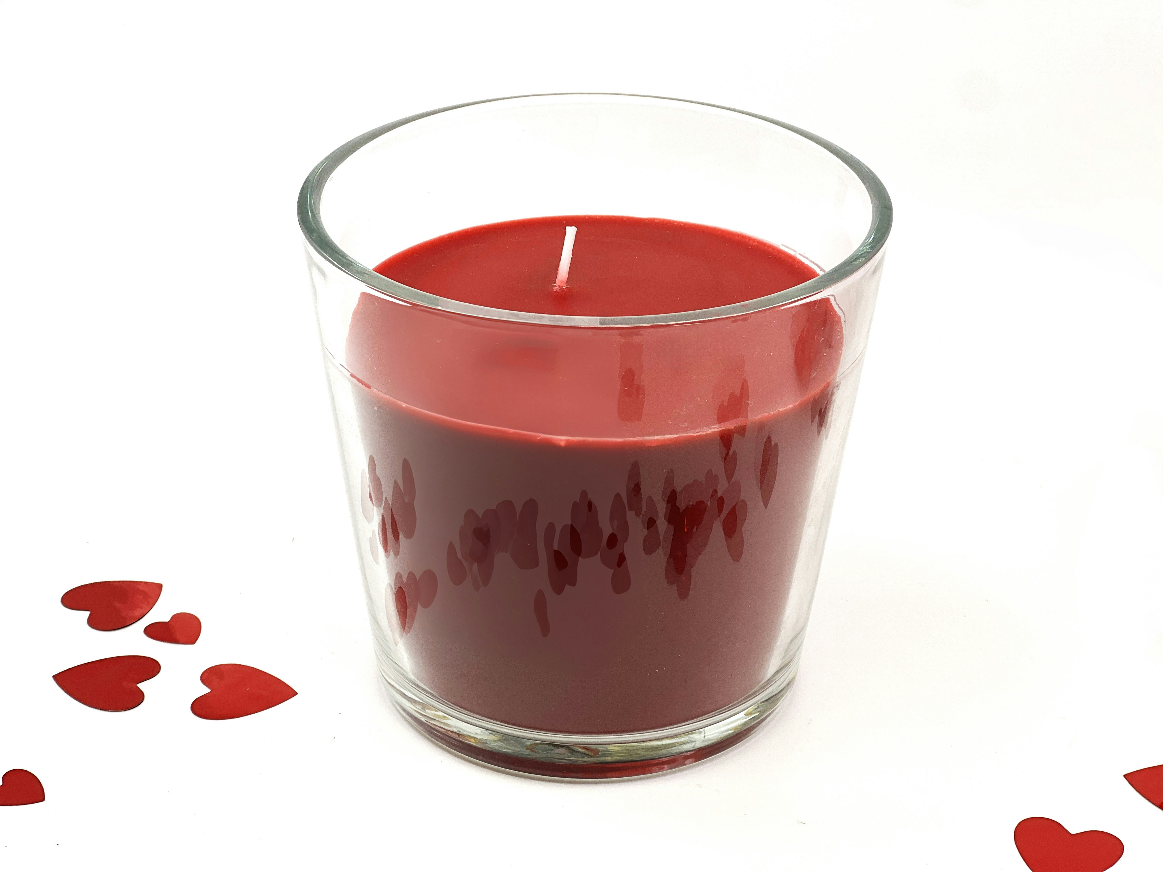 Red candle in glass with heart confetti