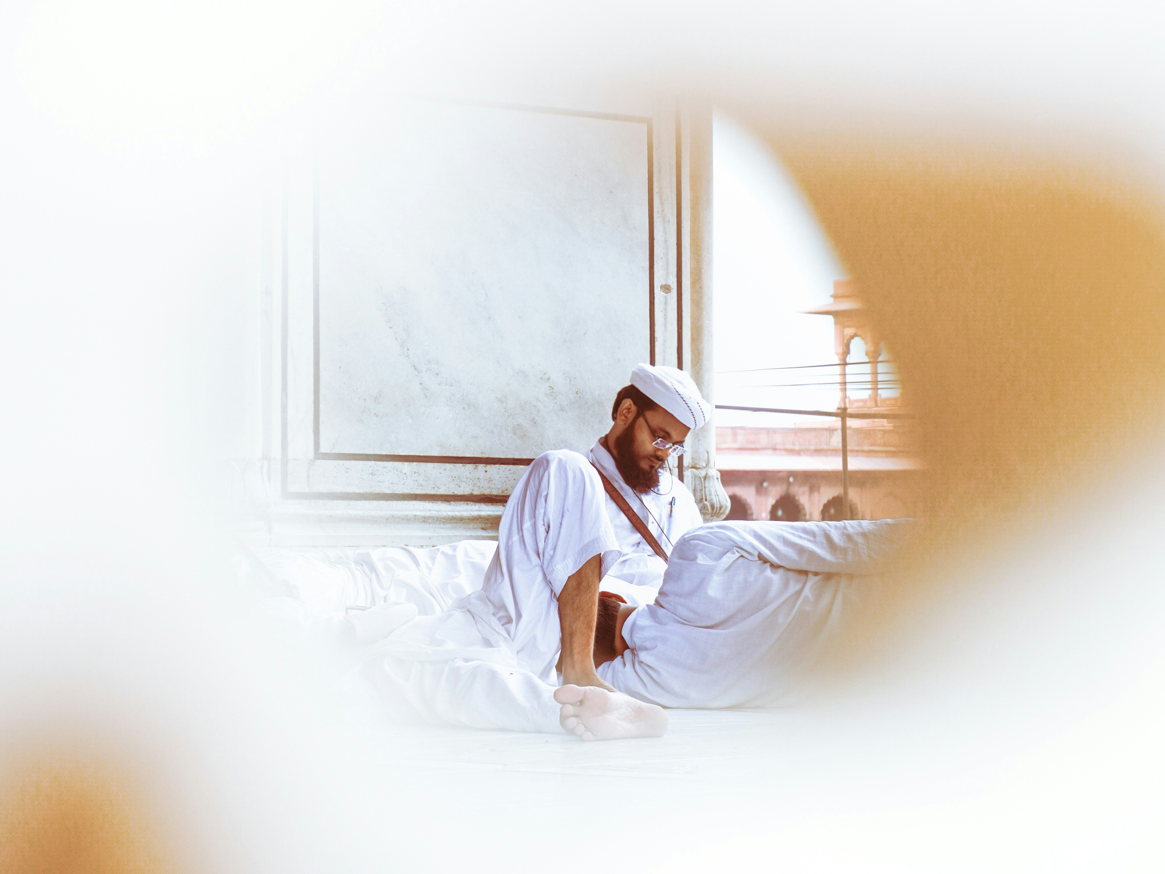 A man in traditional clothing reads a book indoors.