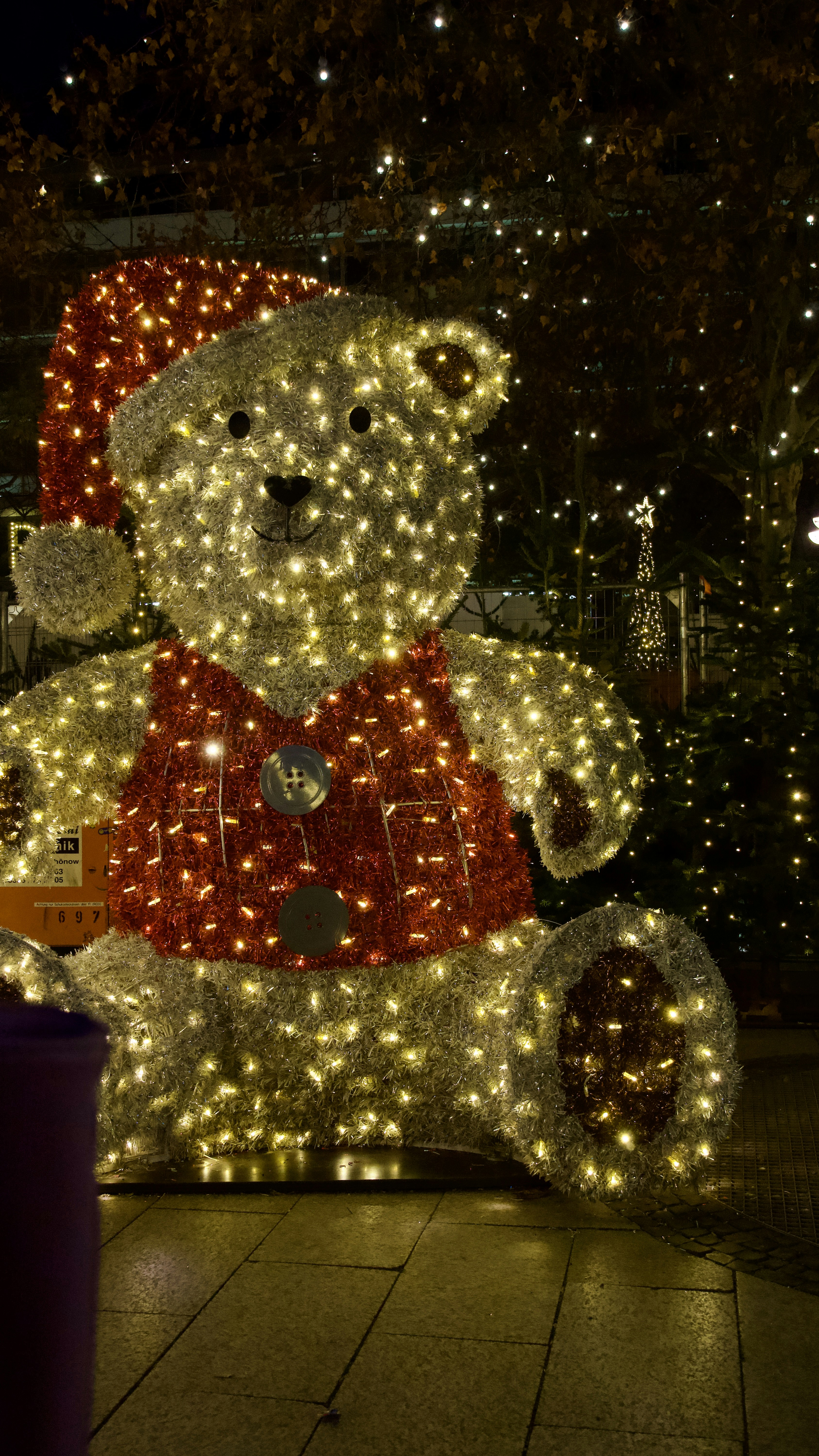 A teddy bear decoration covered in christmas lights.