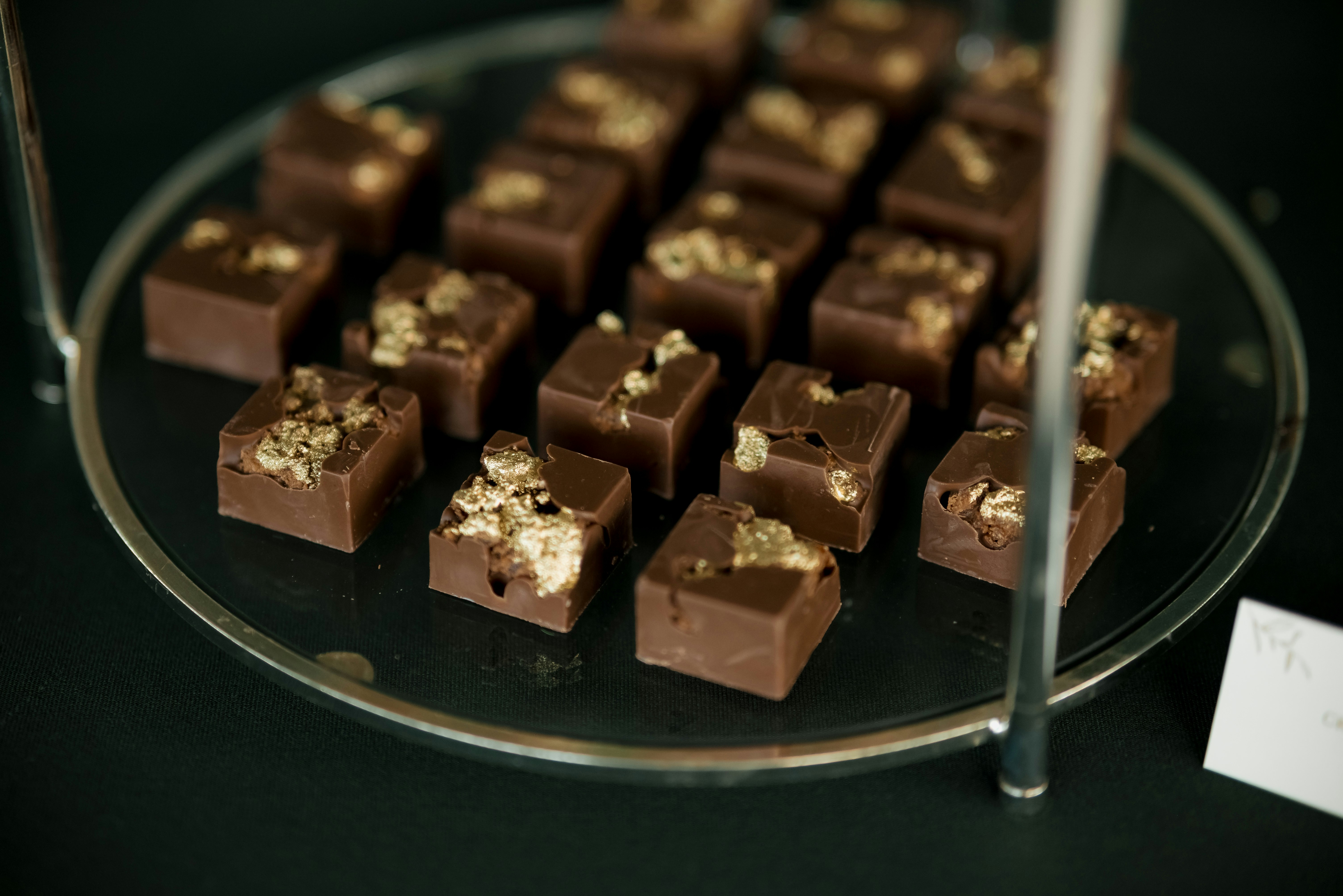 Small chocolate squares topped with nuts on a platter.