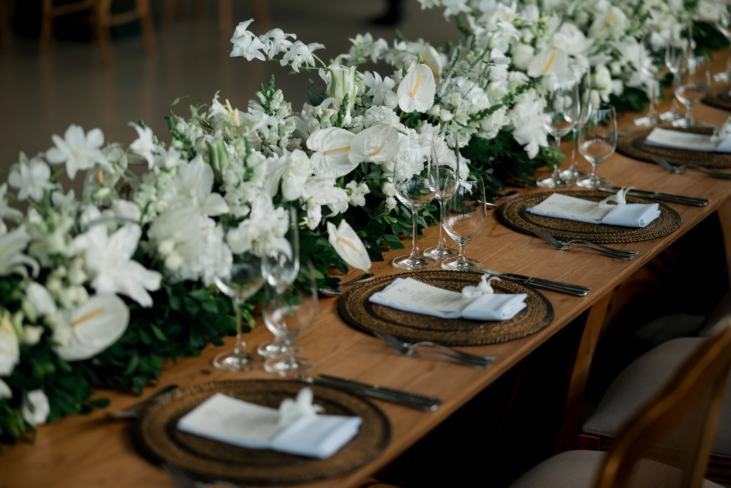 Wedding reception table with white flowers, plates, napkins, cutlery, and glassware