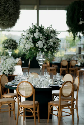 Elegant wedding reception table with floral centerpiece and chairs