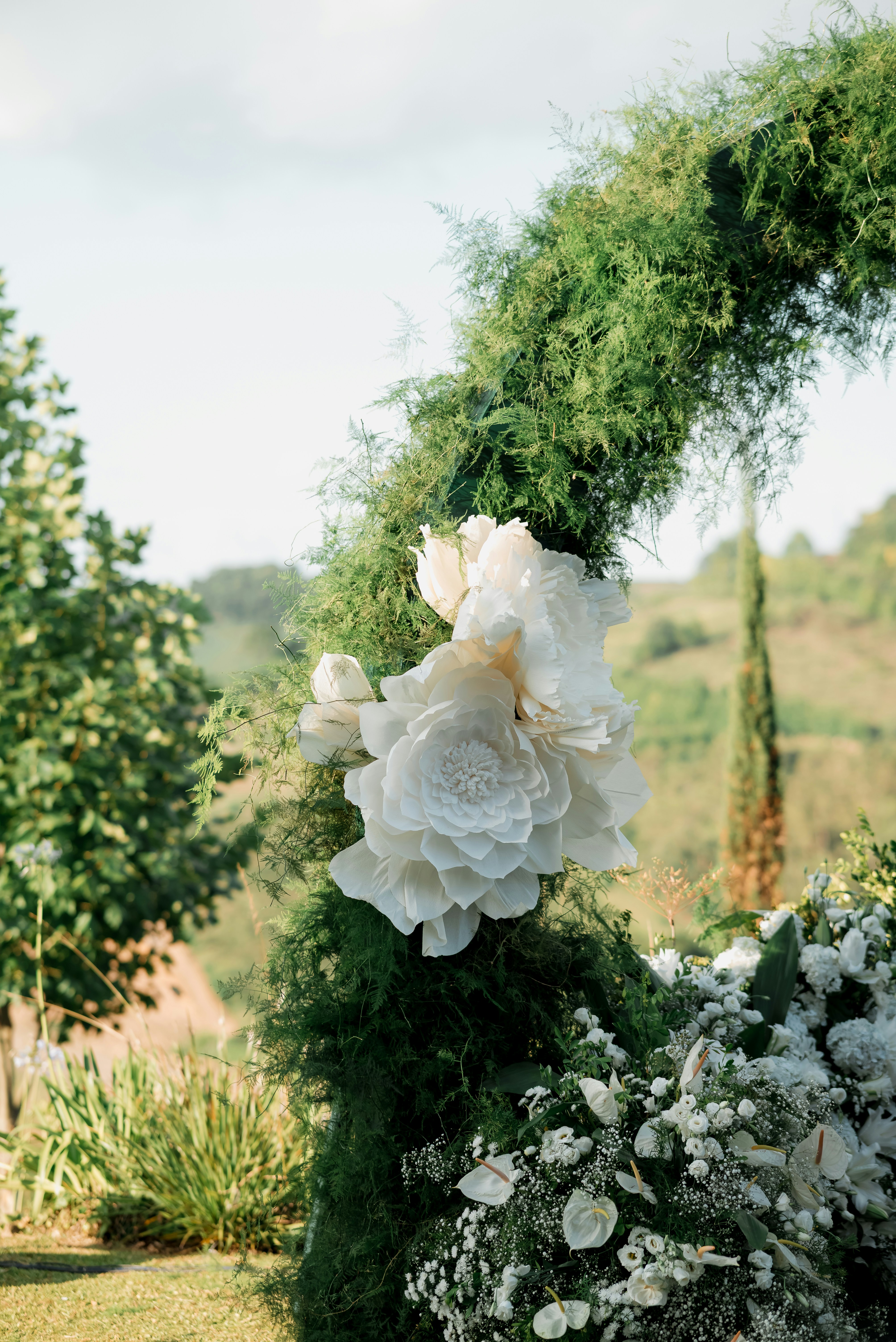 Greenery wedding arch accented with ivory faux flowers