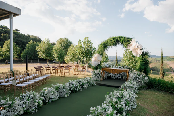 Outdoor wedding ceremony setup with floral arch and green arch