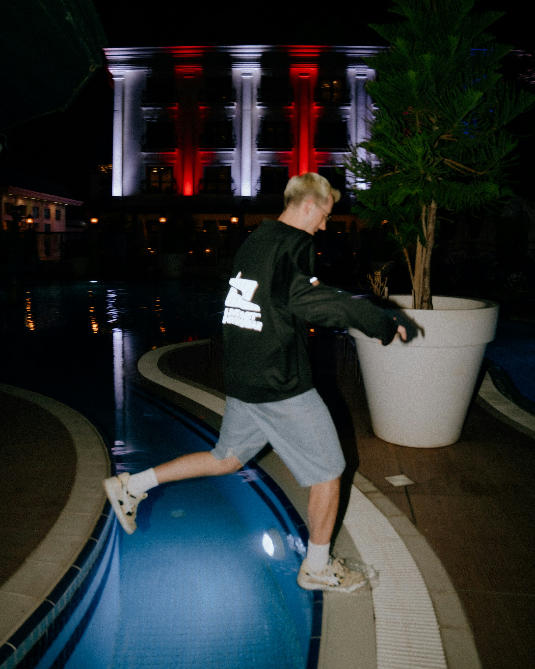 Man in shorts runs near a pool at night
