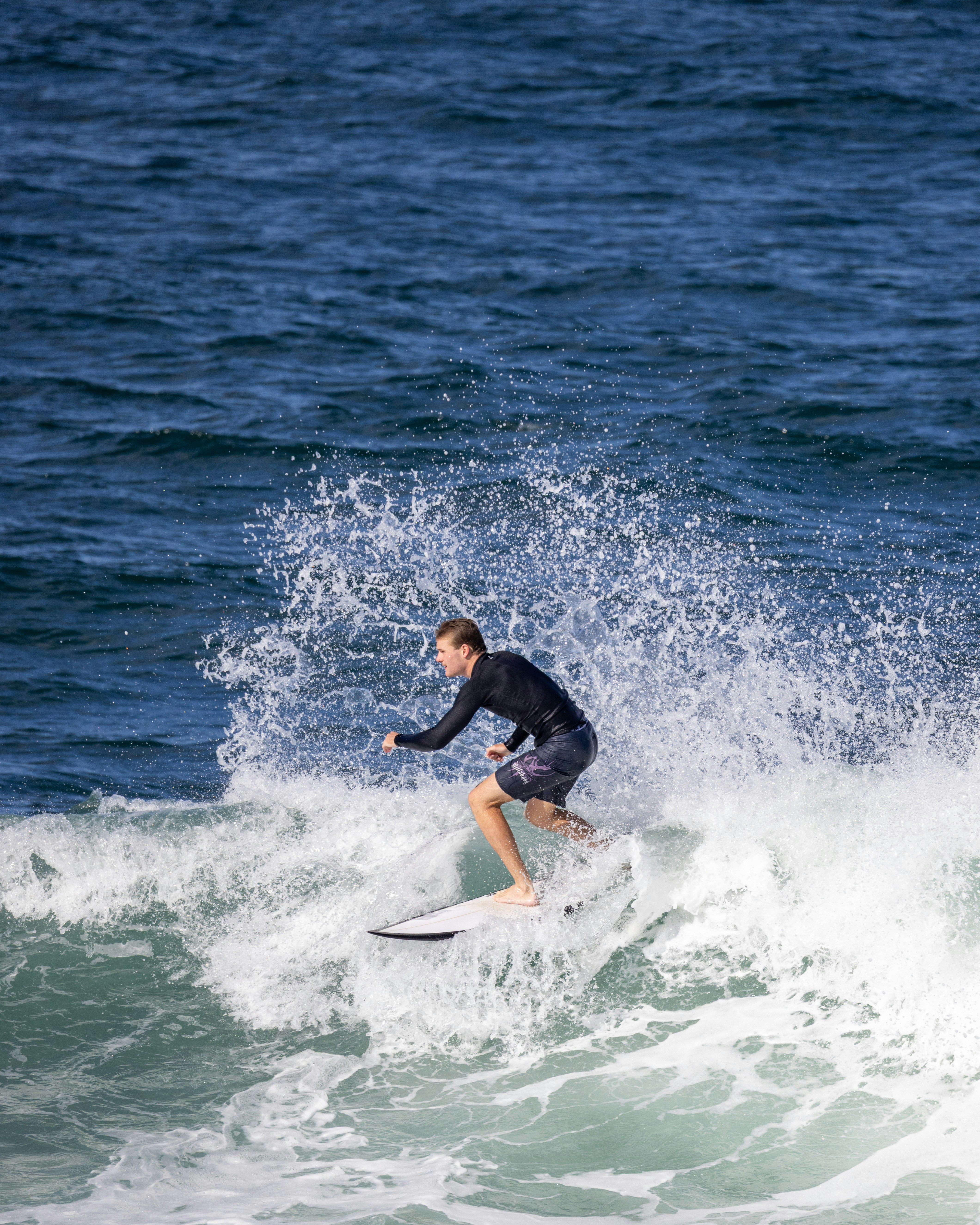 Young surfer riding a wave with splashing water