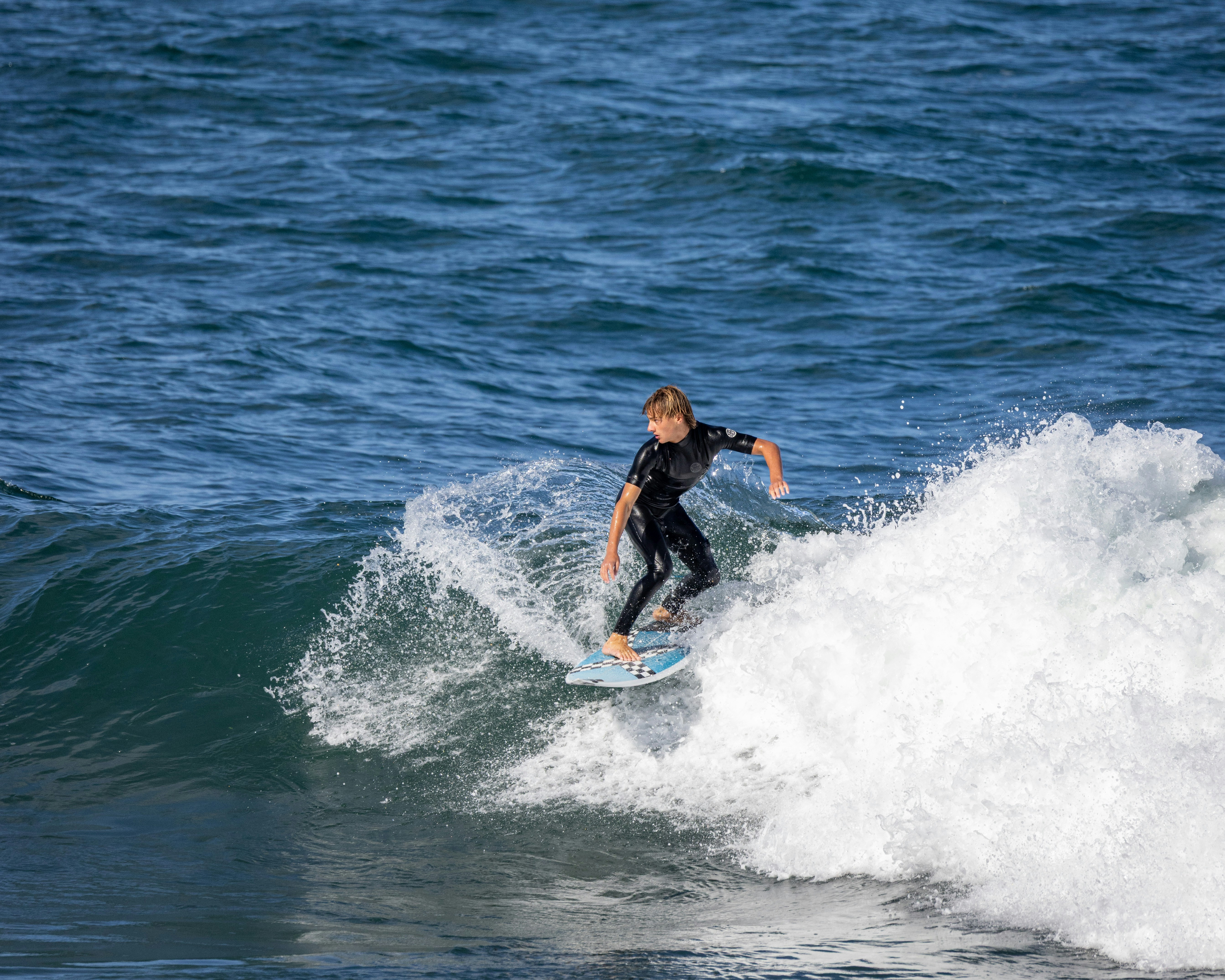 Young surfer riding a wave on a sunny day.