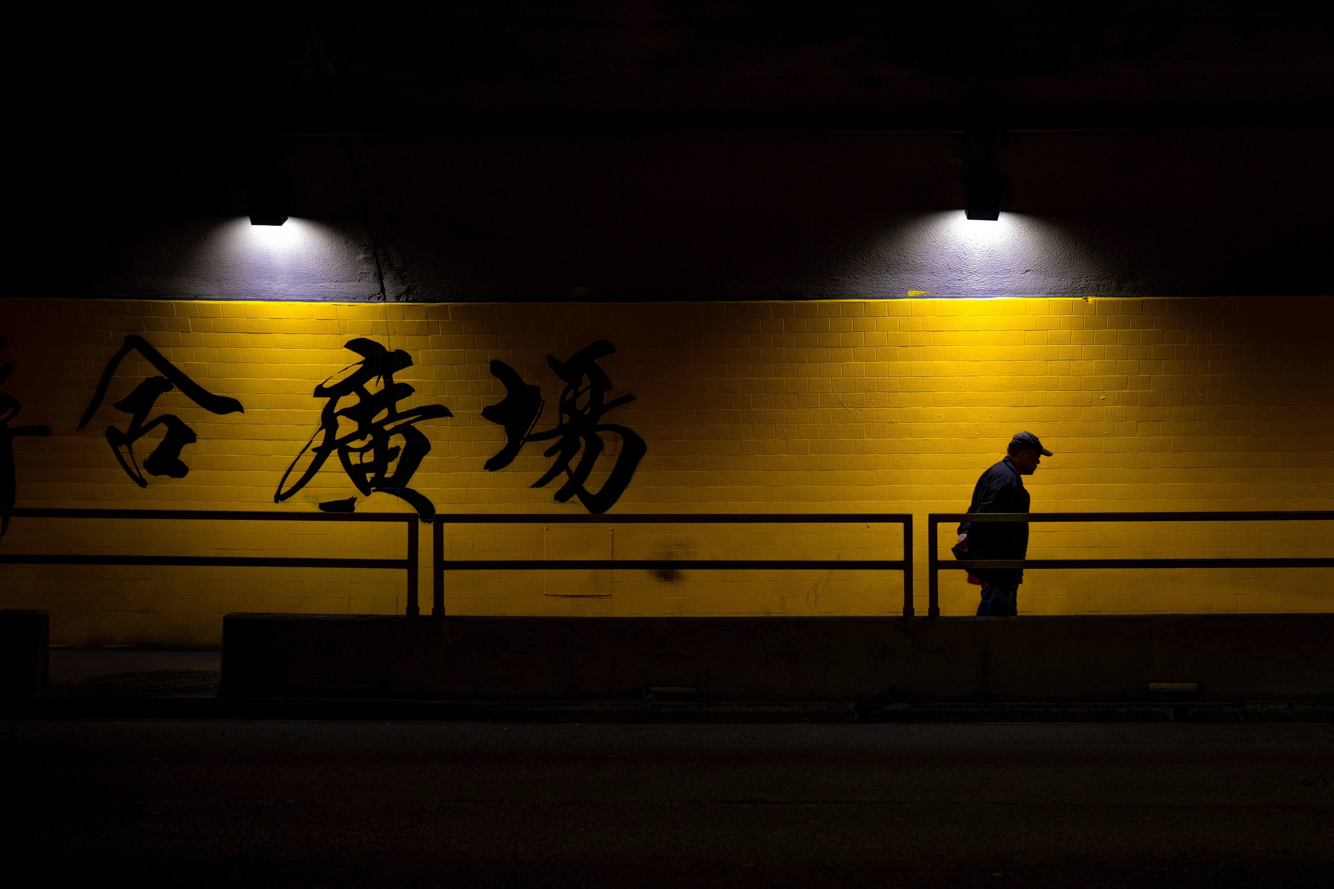 Man walks past yellow wall with chinese characters.