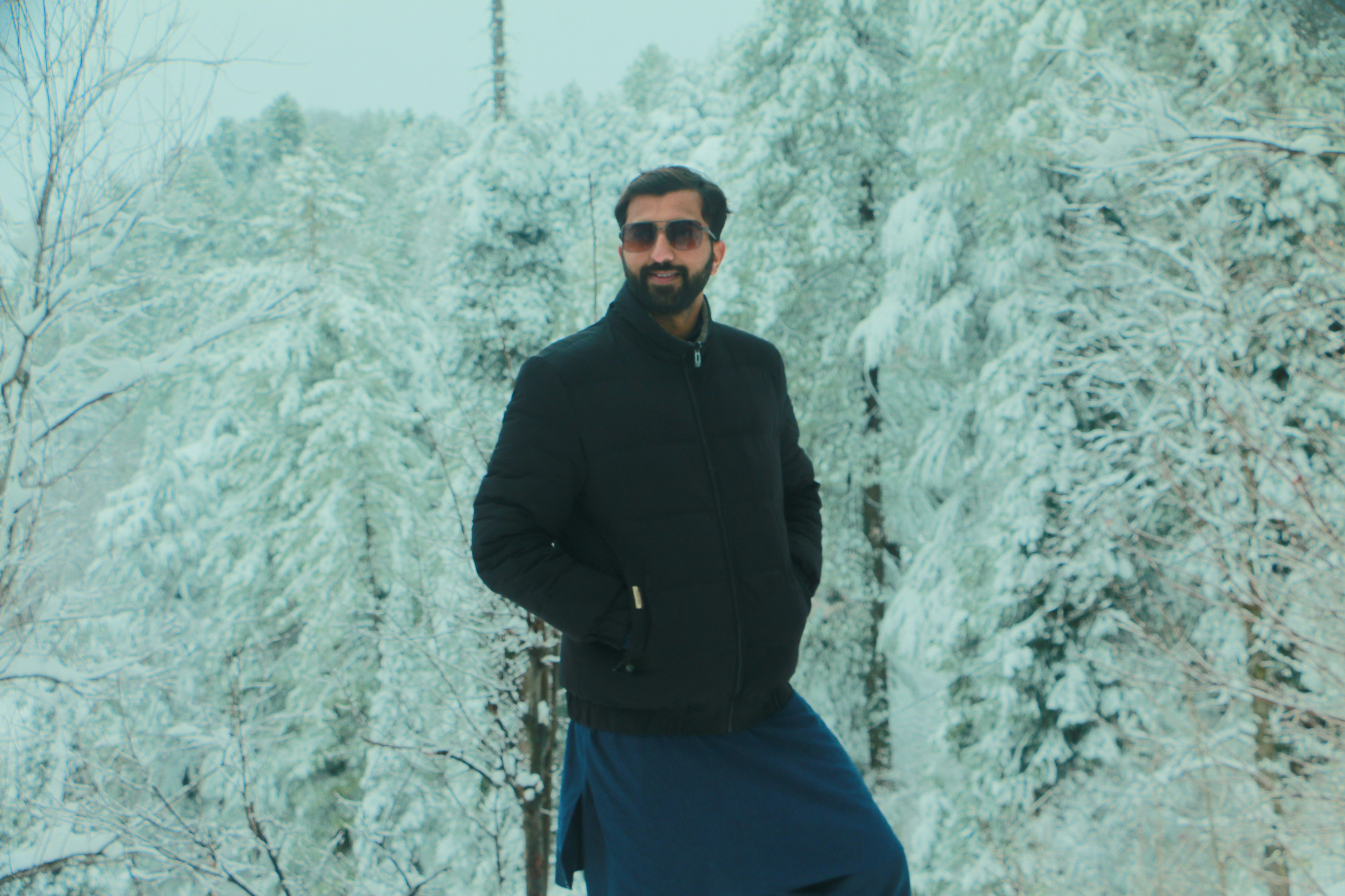 Man in black jacket stands in snowy forest
