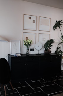 Black sideboard with artwork and plants