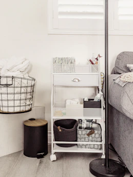 White rolling cart filled with baby supplies and baskets.