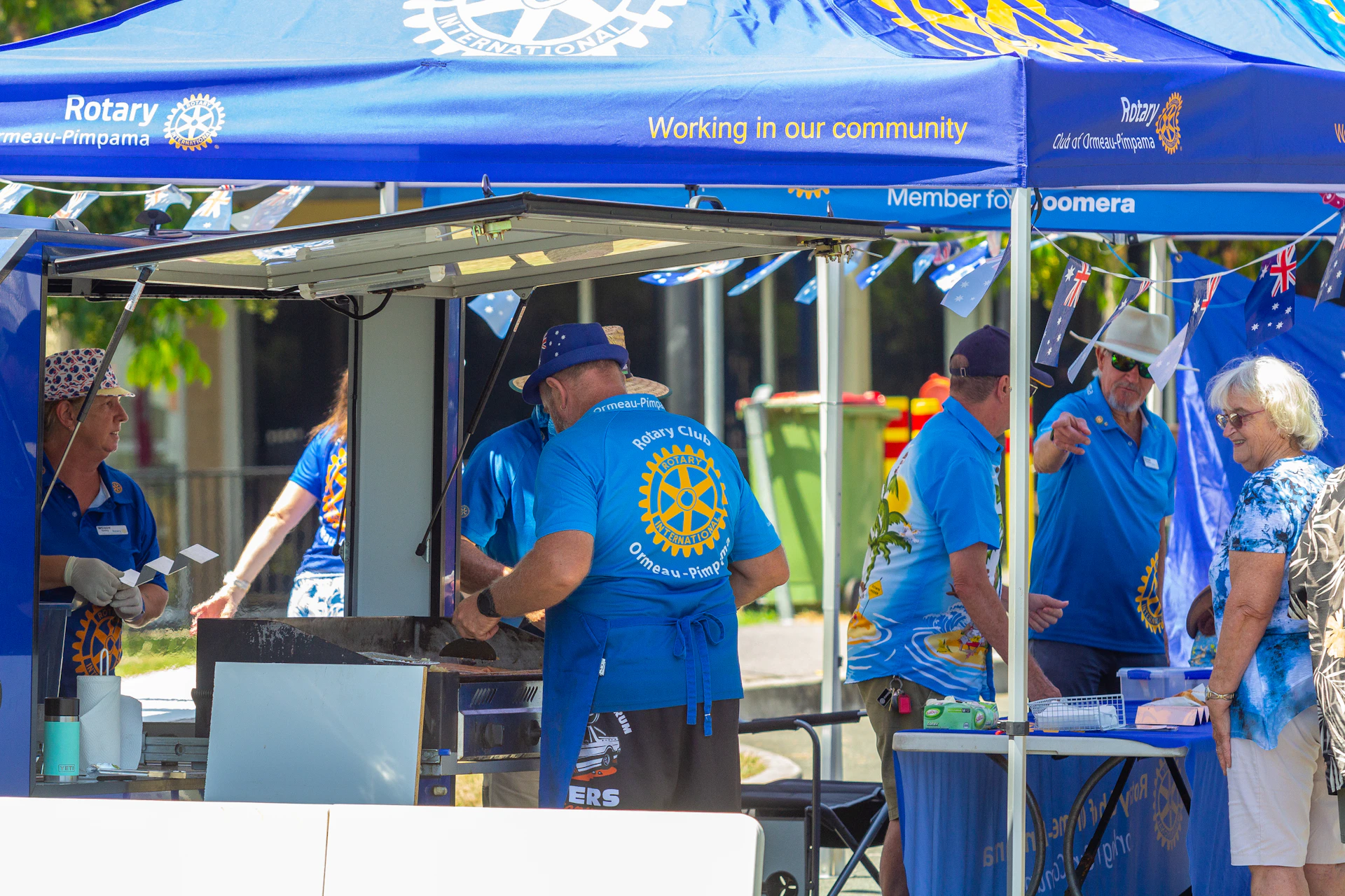 People in blue shirts at an outdoor event.