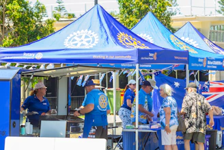 People gathered at a blue rotary club outdoor event.