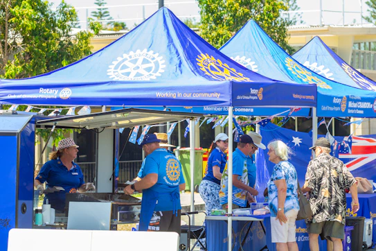 People gathered at a blue rotary club outdoor event.