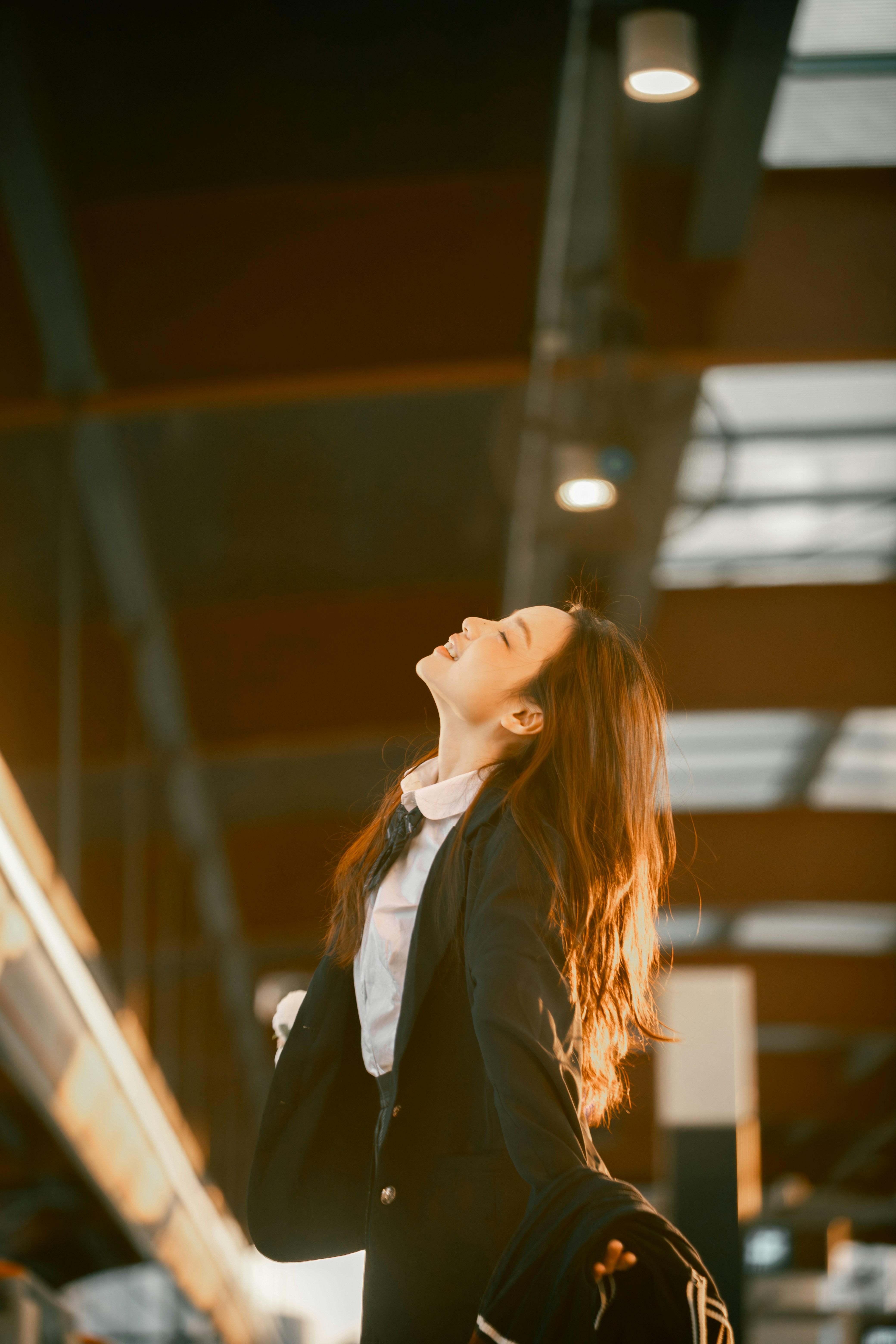 Young woman in business attire looking up joyfully.