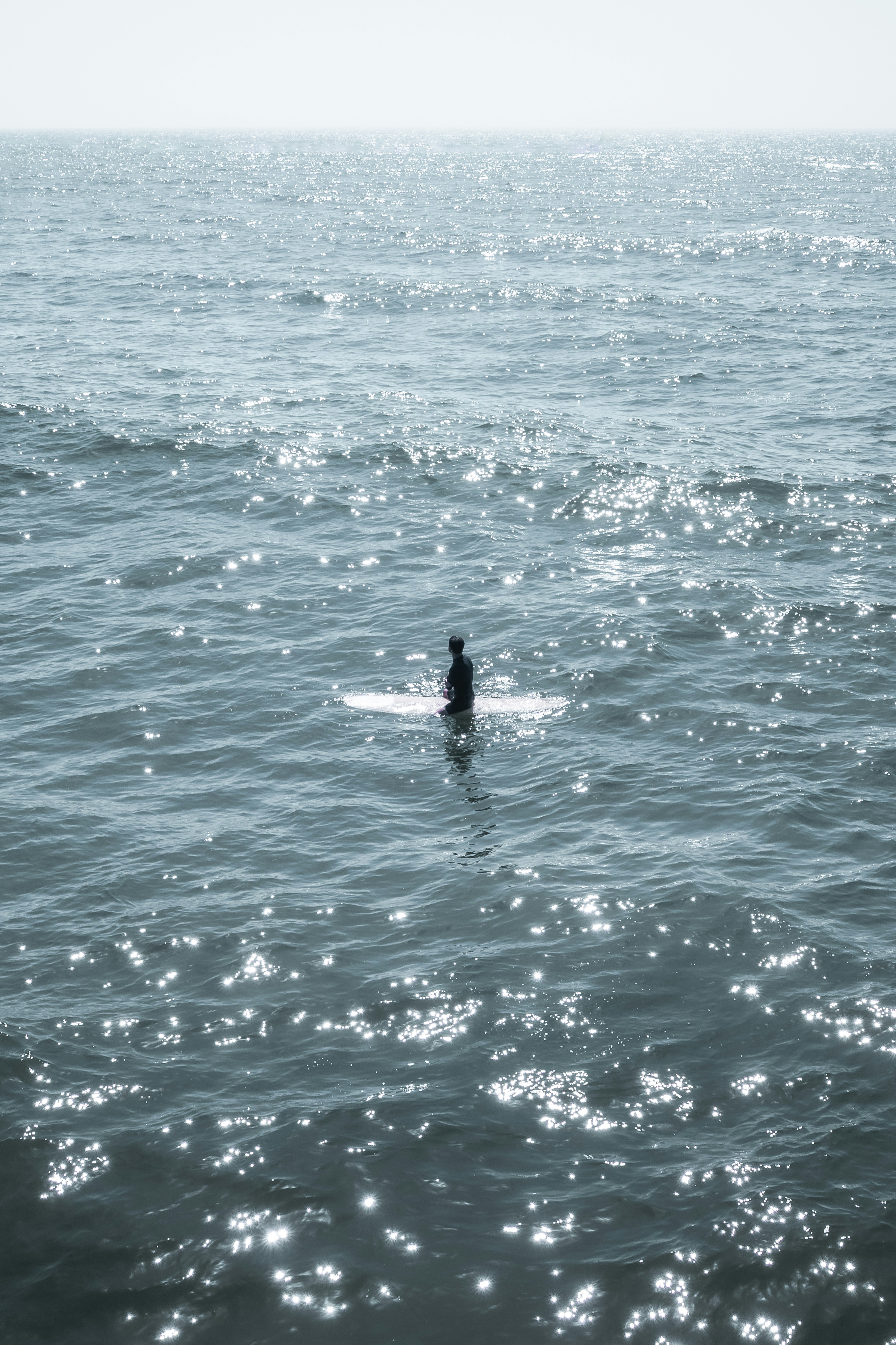 Surfer sitting on surfboard in sparkling ocean waves