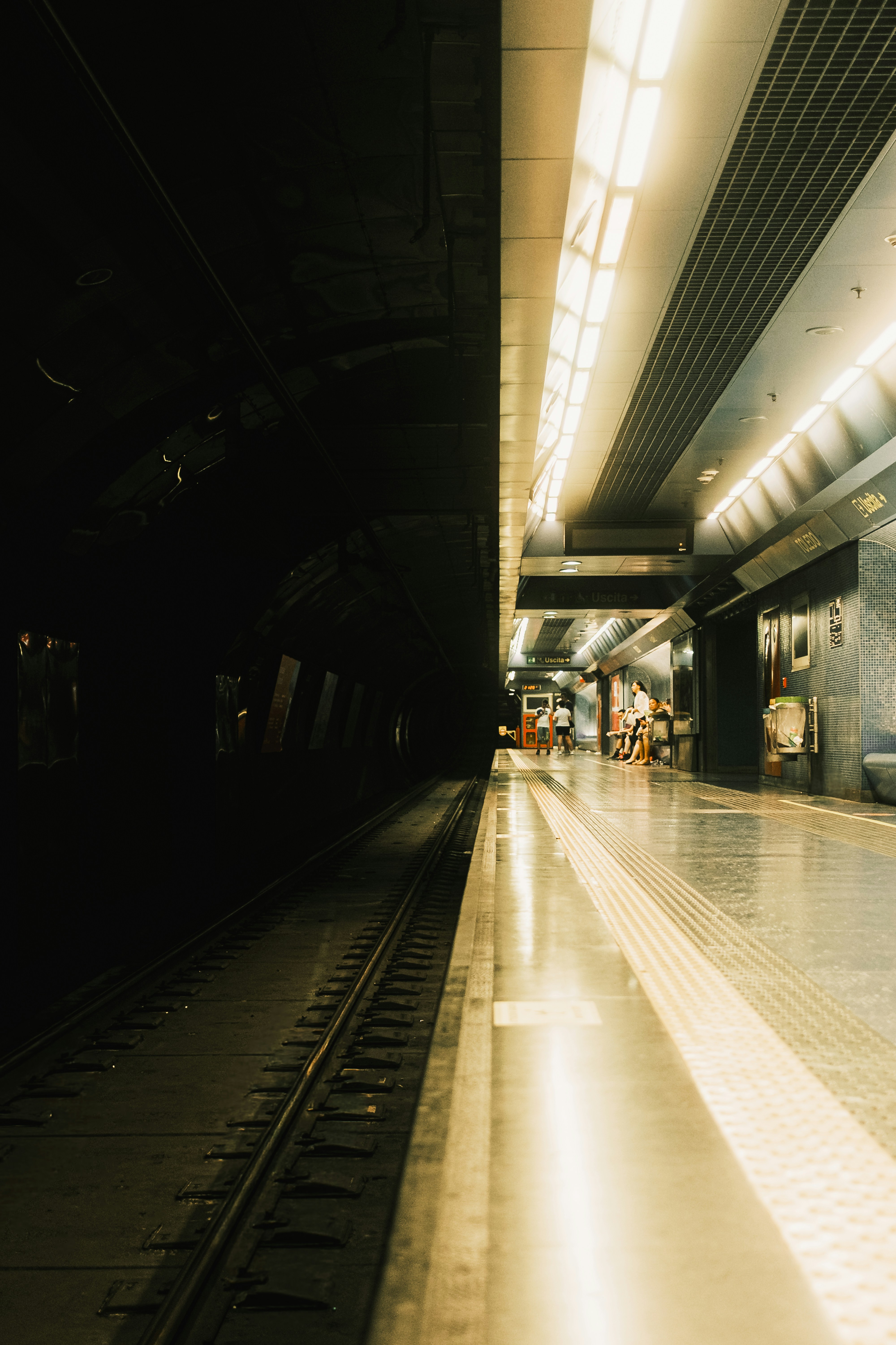 A dimly lit subway station platform with train tracks.