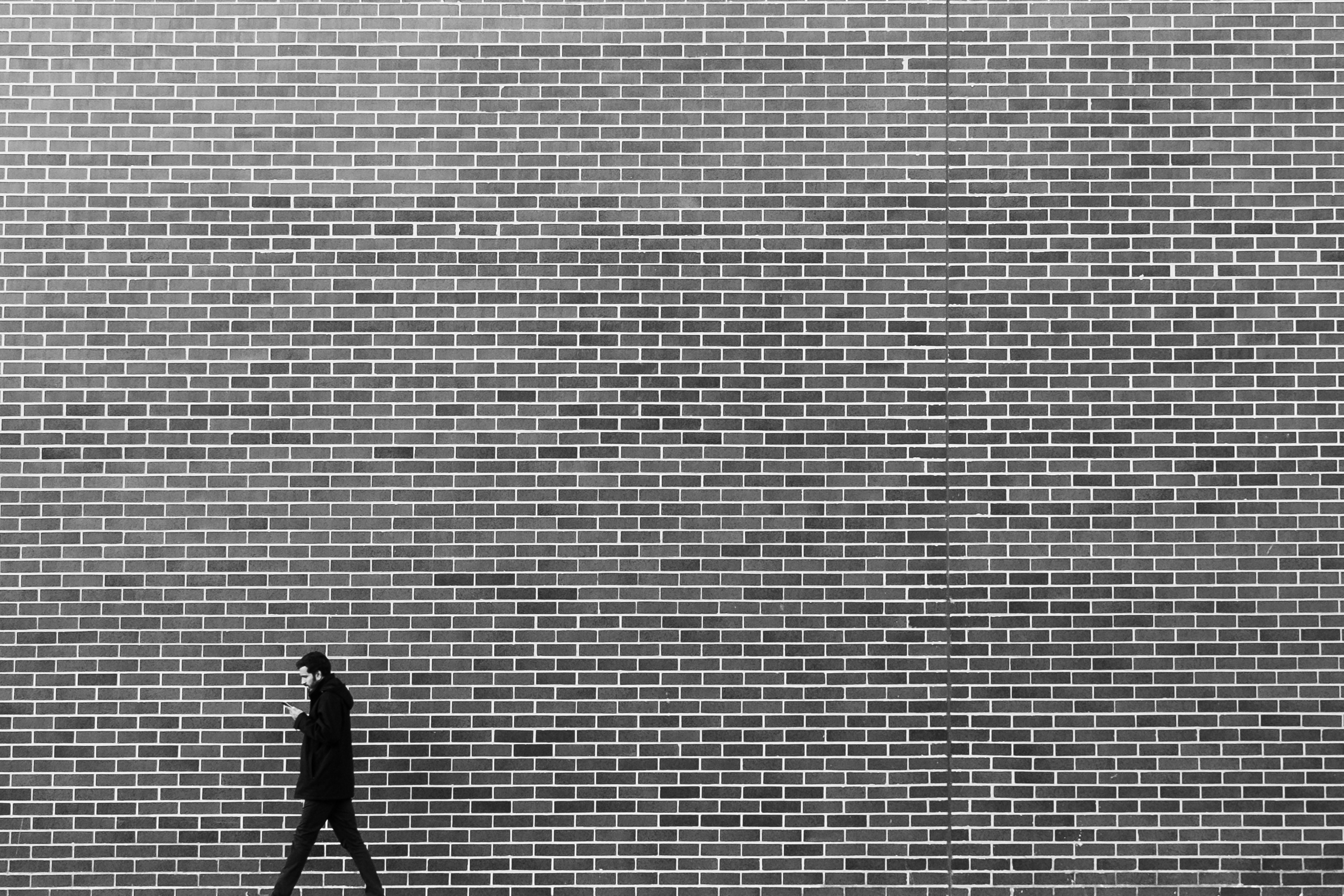 Man walks past a large brick wall