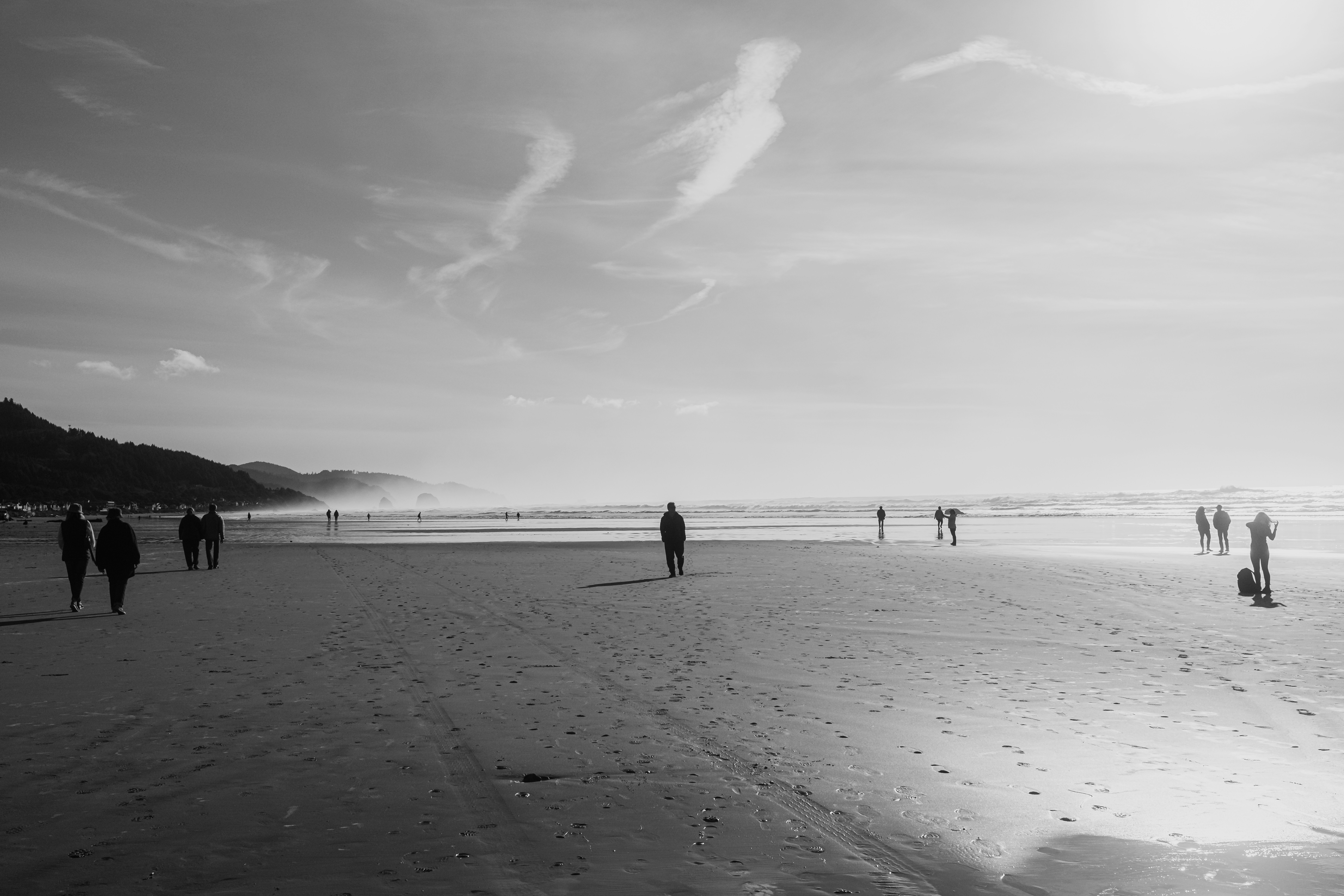 People walking on a wide sandy beach near the ocean.