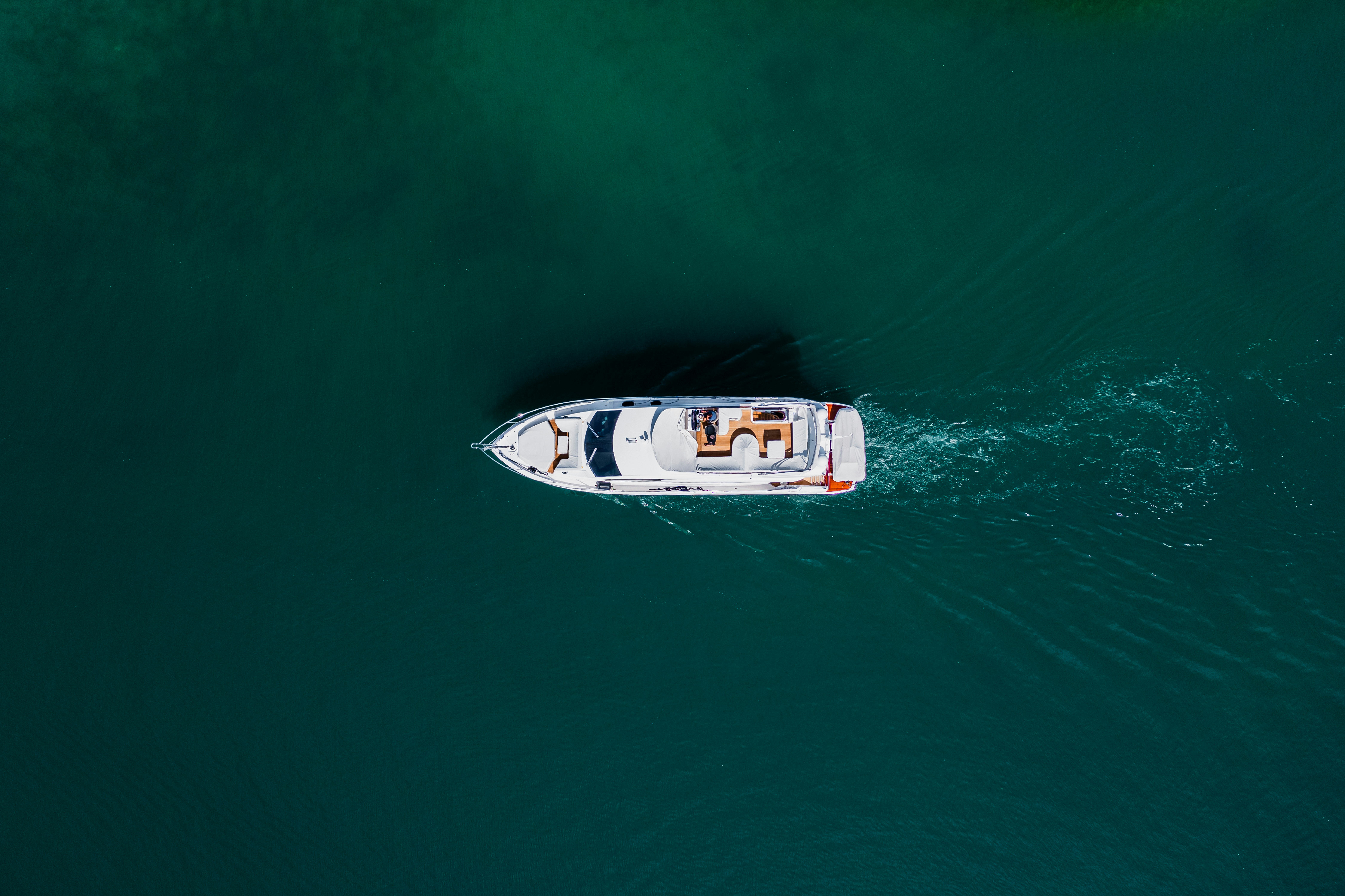 White motorboat cruising on dark teal water