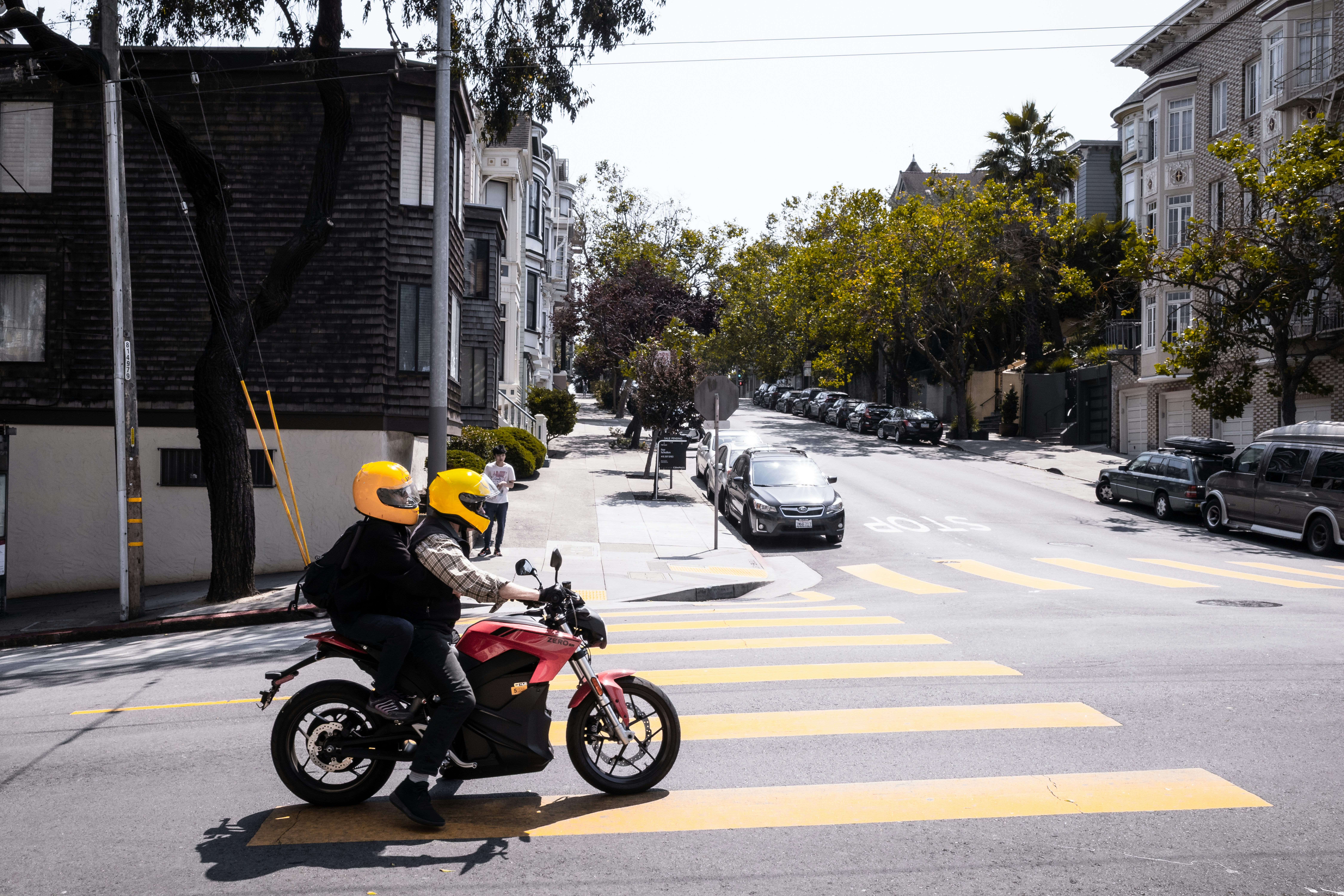 Two people on a motorcycle crossing a street.