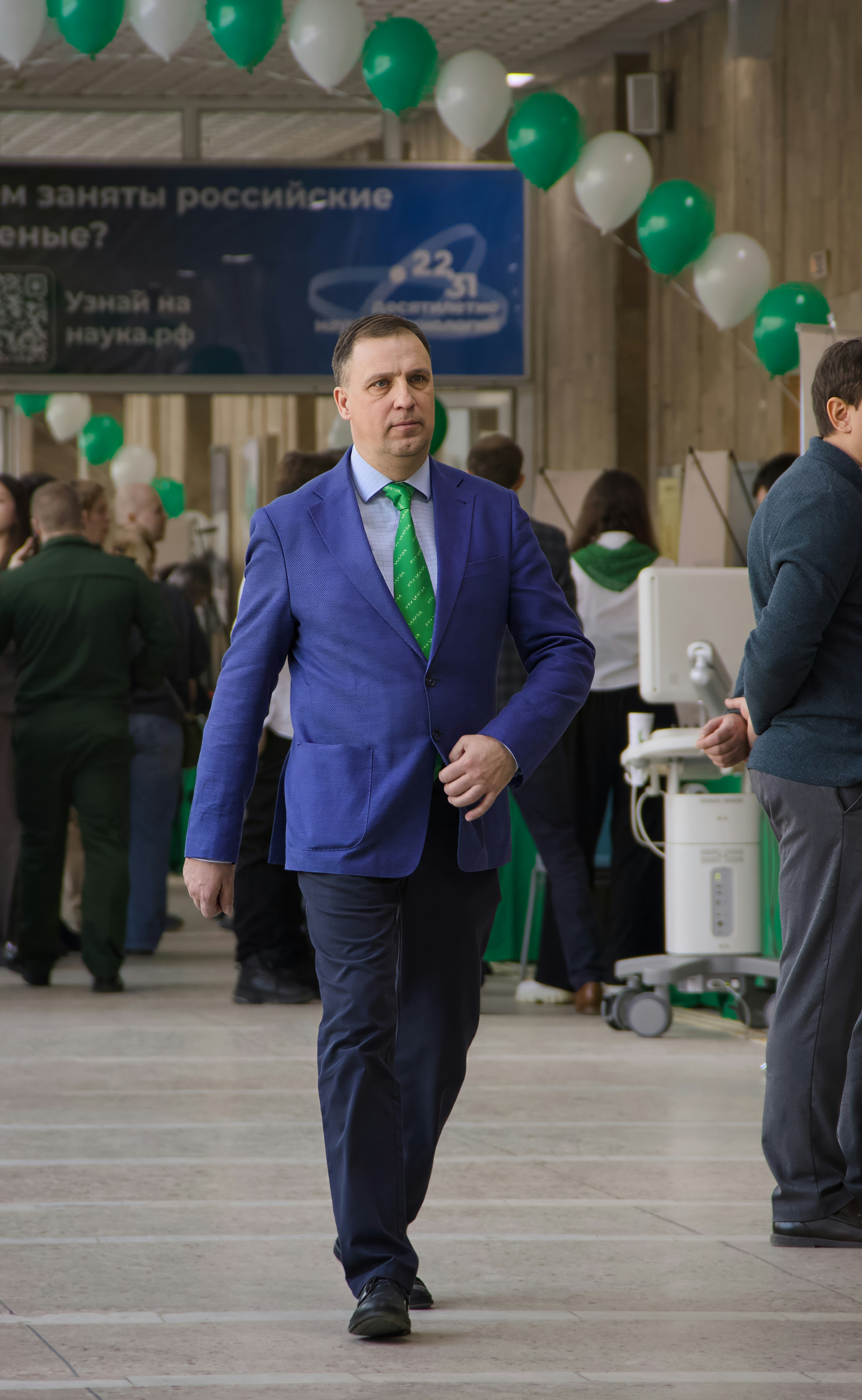 A man in a blue suit walks down a hallway.