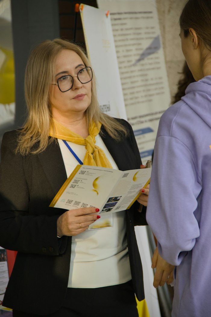 Woman holding an open brochure while talking to a visitor