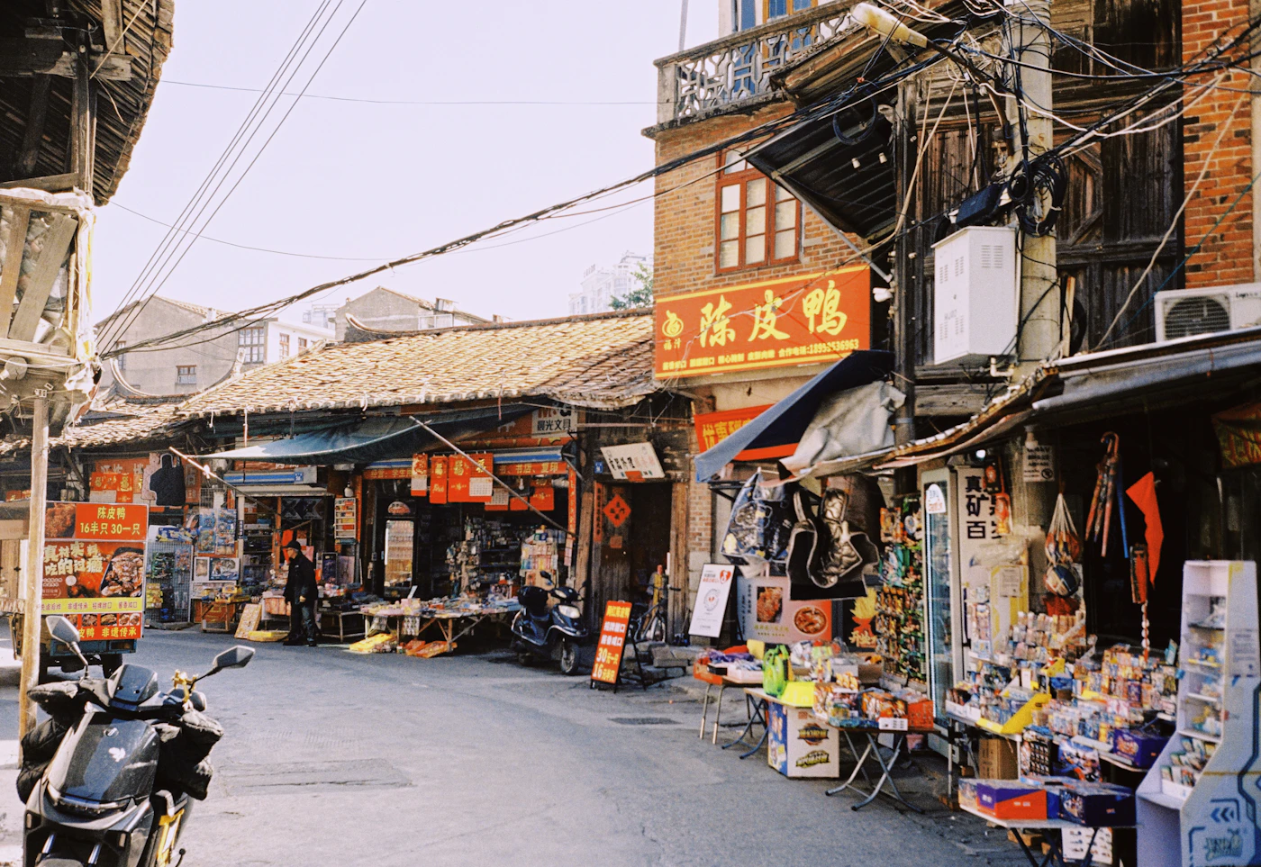 A row of small shops and parked scooters