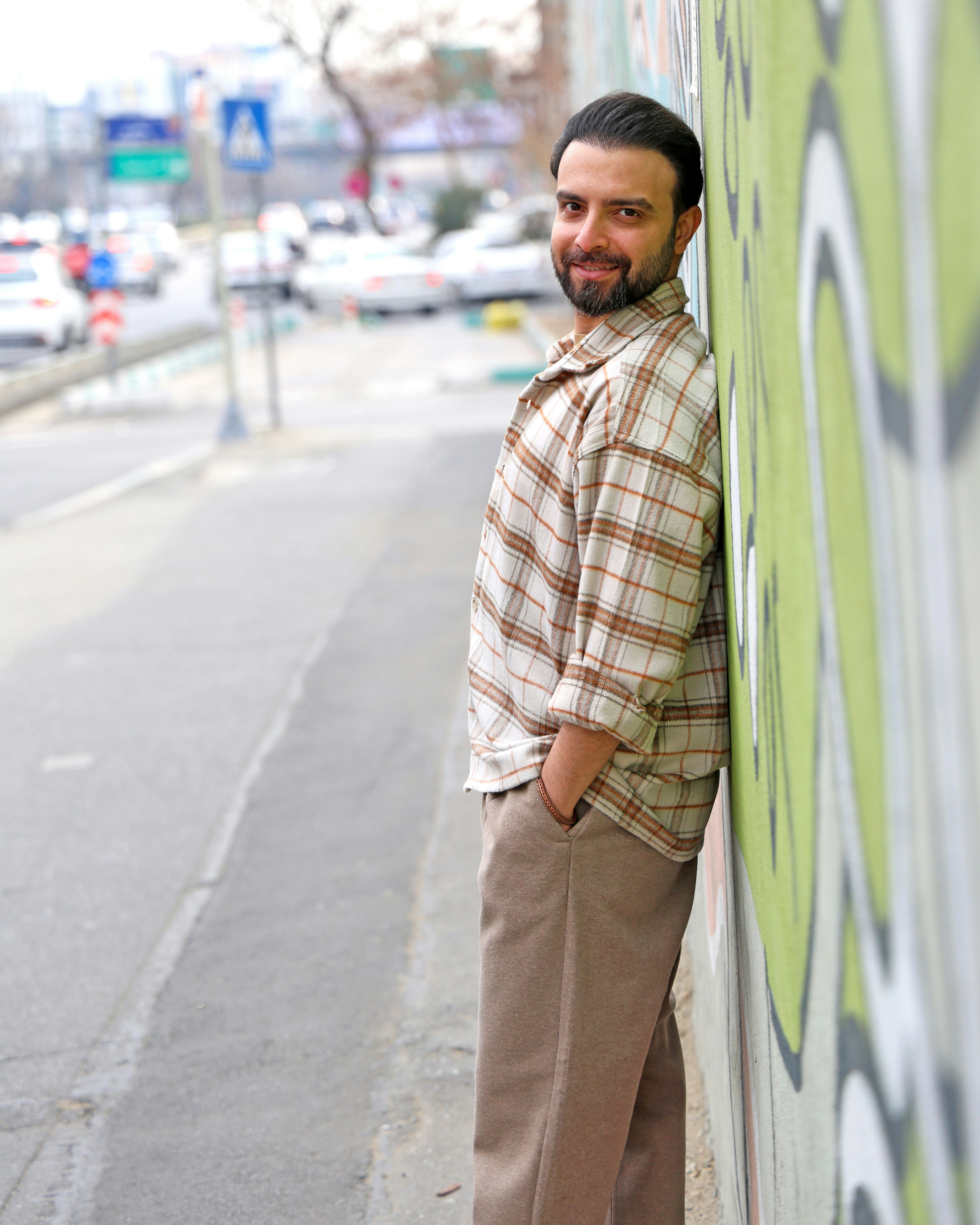 Uomo appoggiato al muro dei graffiti in strada cittadina.