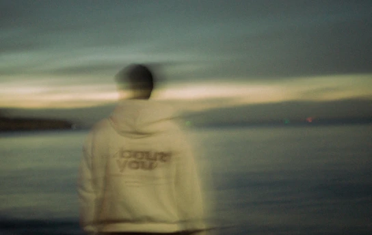 Person in hoodie looking out at the ocean.