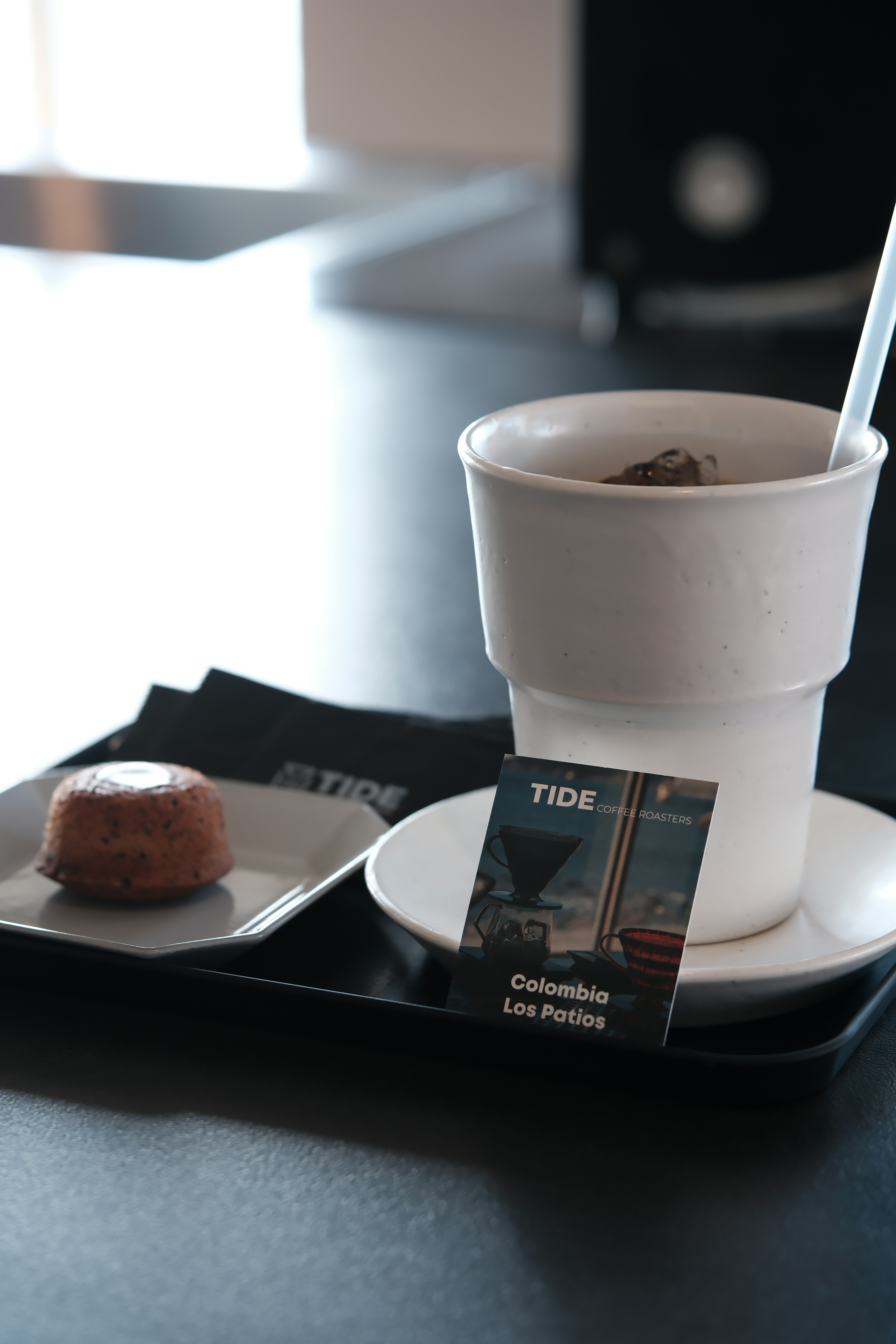 A white cup of coffee with a small pastry.